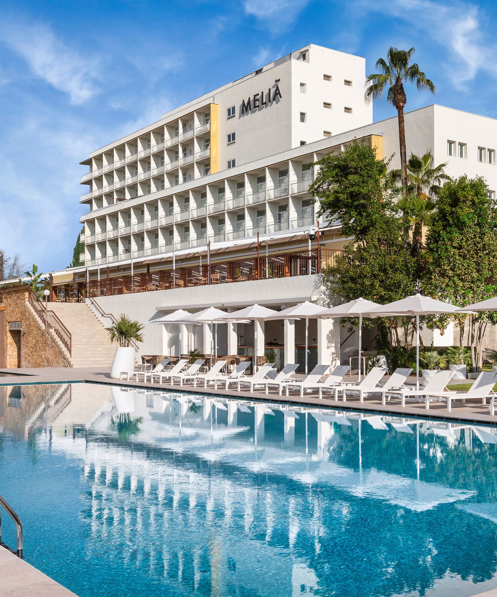 a pool with umbrellas and chairs in front of a building