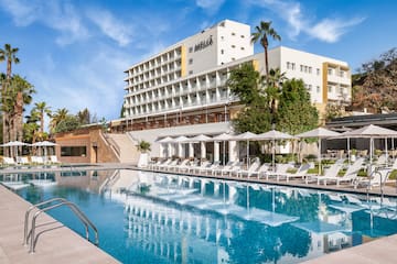 a pool with umbrellas and chairs in front of a building