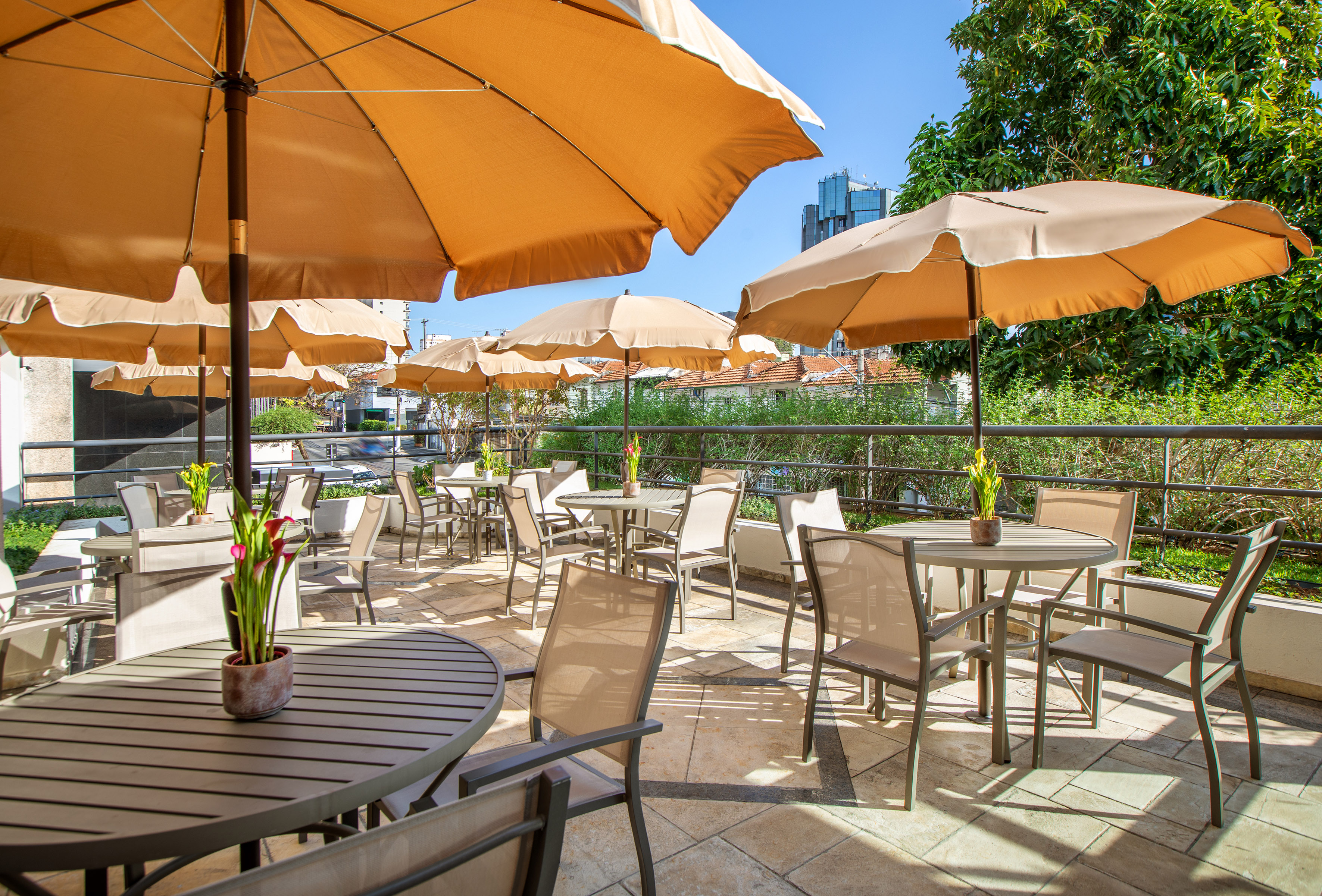 Shaded outdoor dining patio with multiple tables and large umbrellas.