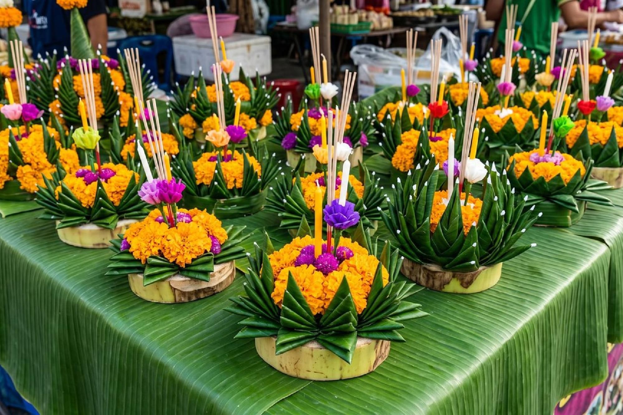 Loy Krathong festival arrangements: marigolds, candles, incense, banana leaves.