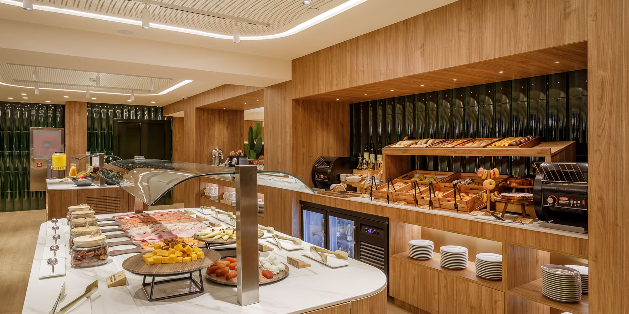 Modern hotel breakfast buffet with pastries, cold cuts, cheeses, and juices.