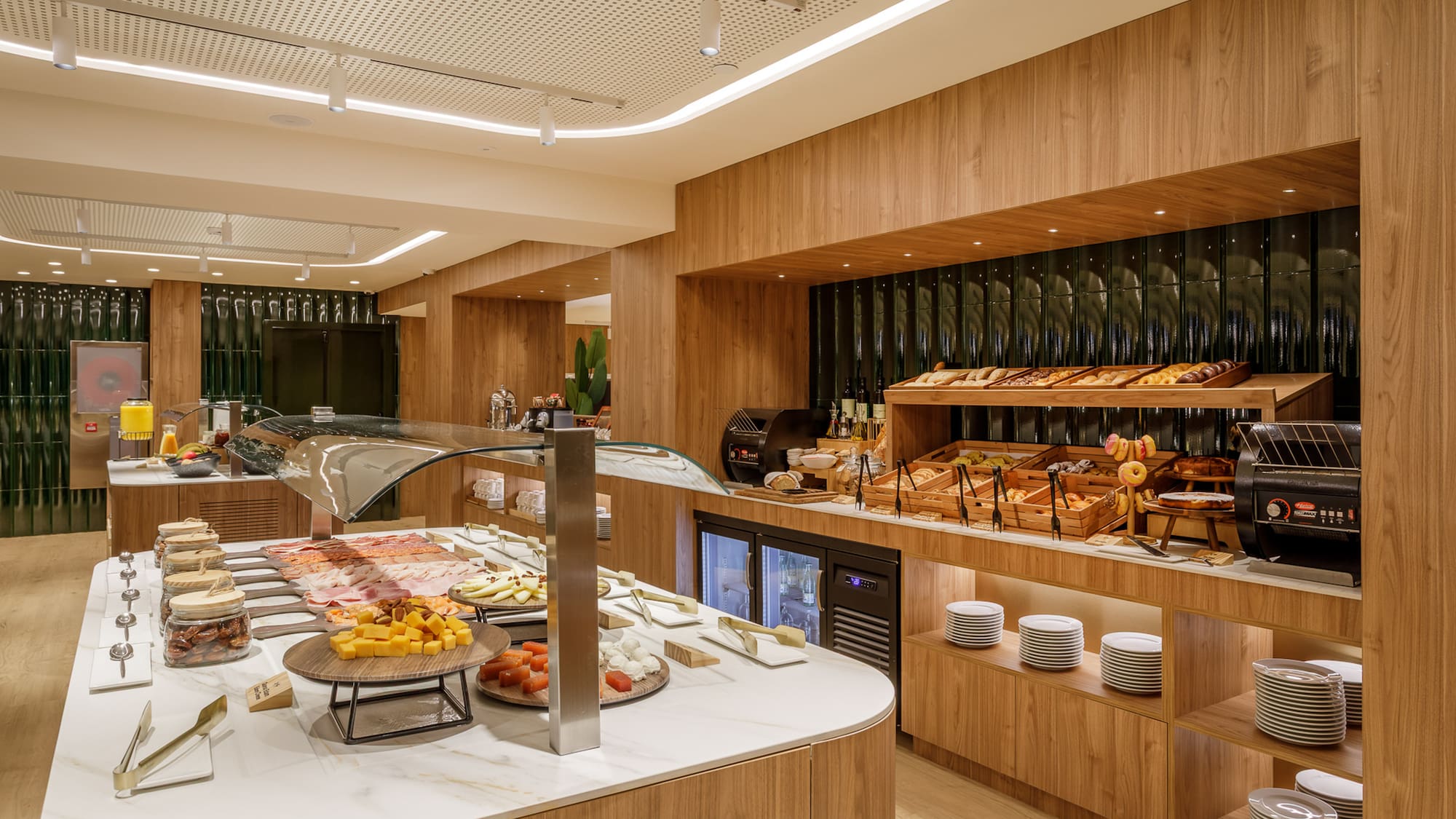 Modern hotel breakfast buffet with pastries, cold cuts, cheeses, and juices.