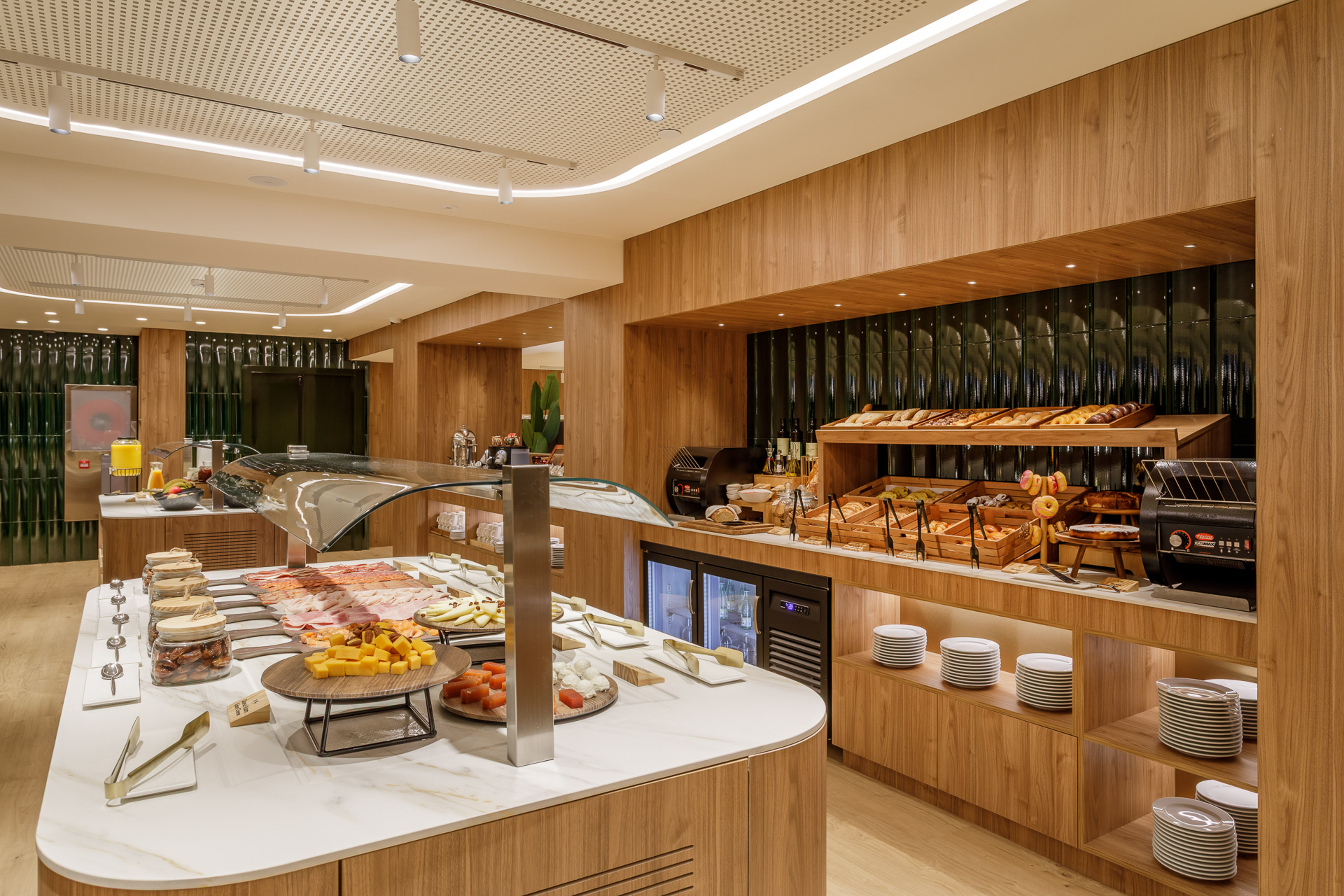 Modern hotel breakfast buffet with pastries, cold cuts, cheeses, and juices.