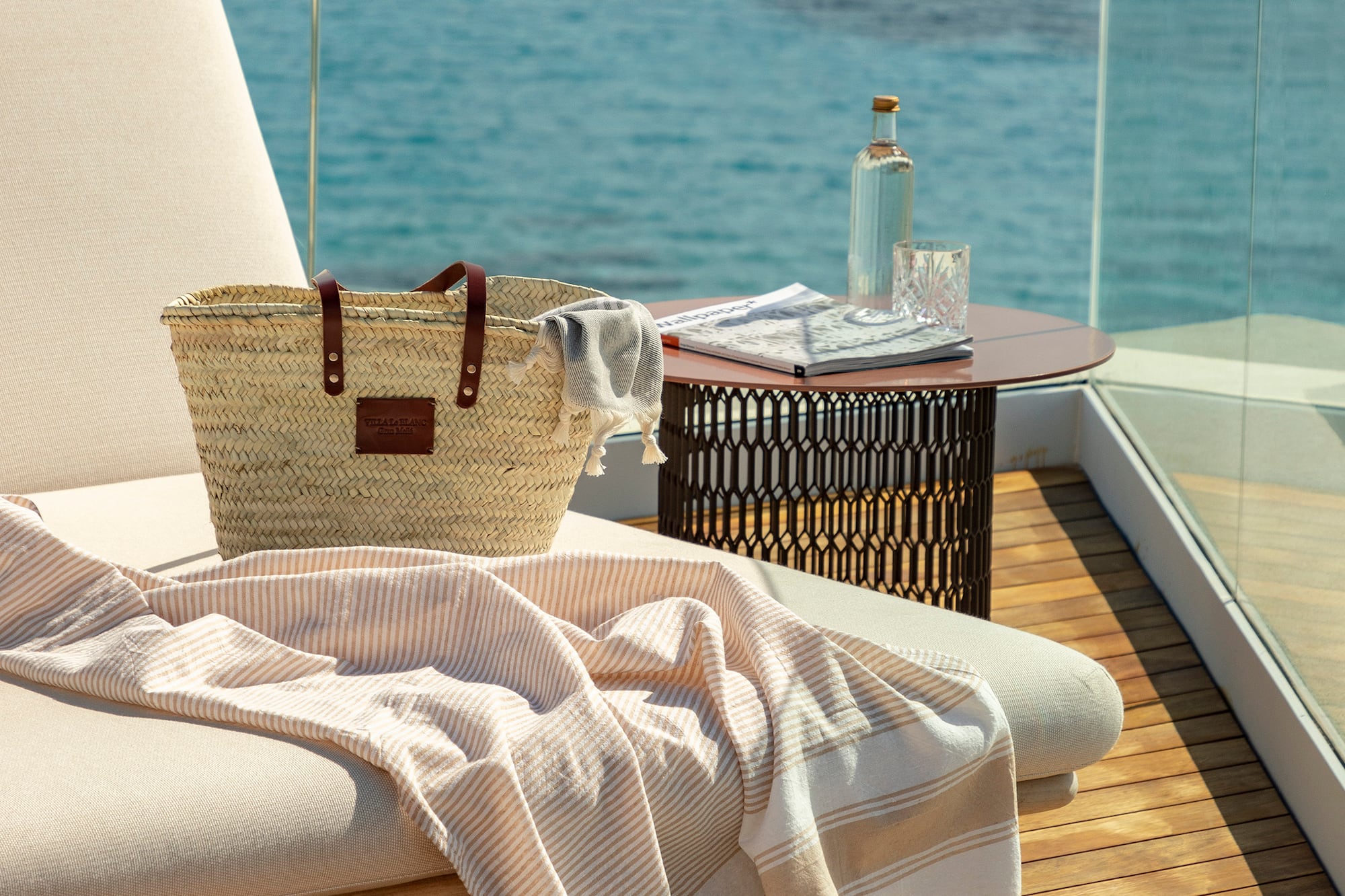 a beach chair with a towel and a bag on a deck overlooking the water