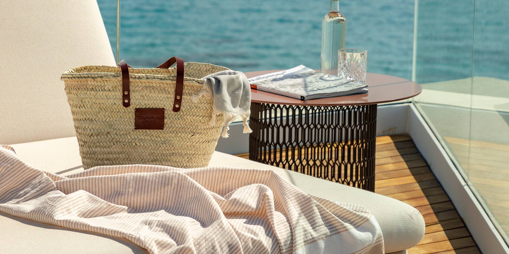 a beach chair with a towel and a bag on a deck overlooking the water