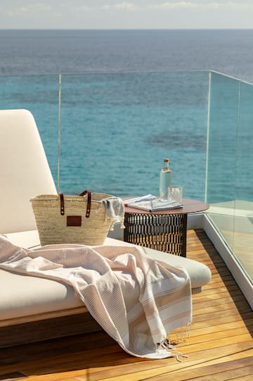 a beach chair with a towel and a bag on a deck overlooking the water