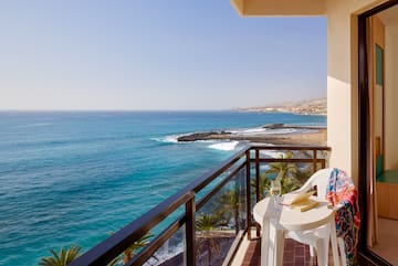 a balcony with a table and chairs overlooking the ocean
