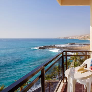 a balcony with a table and chairs overlooking the ocean