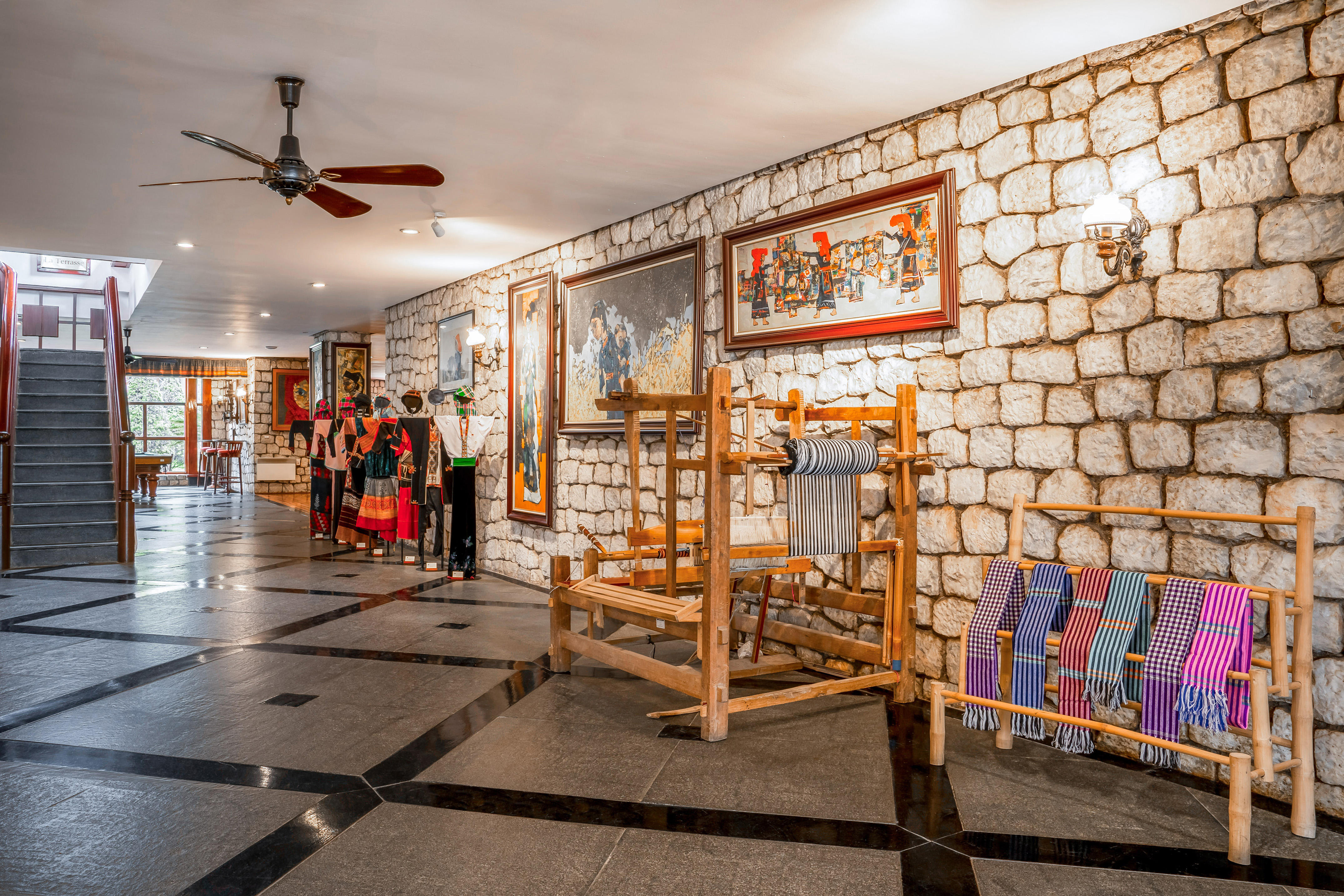 Traditional textiles, clothing, and loom in a stone-walled cultural gallery.