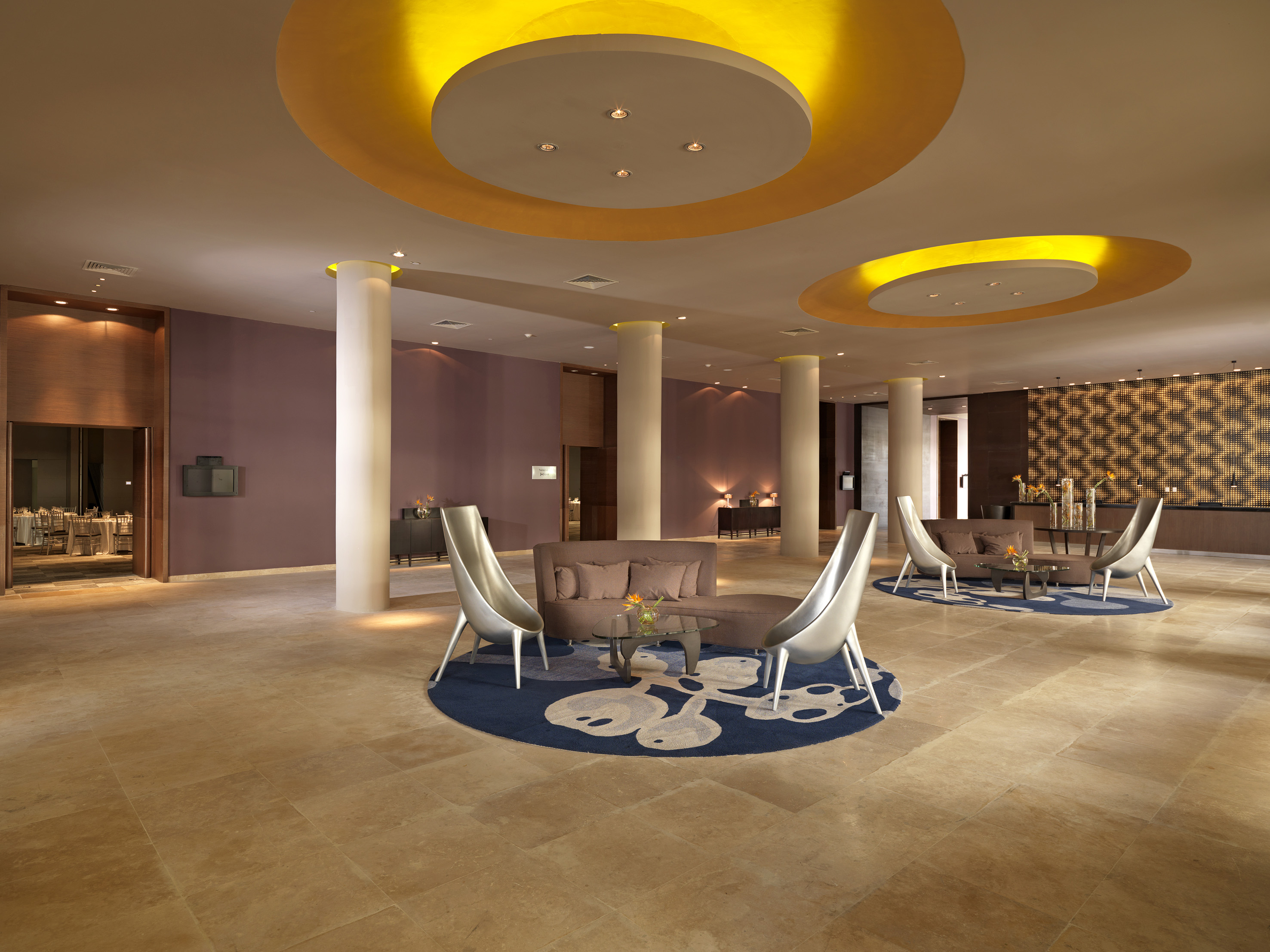 Modern hotel lobby lounge with contemporary seating, warm lighting, and tiled floor.