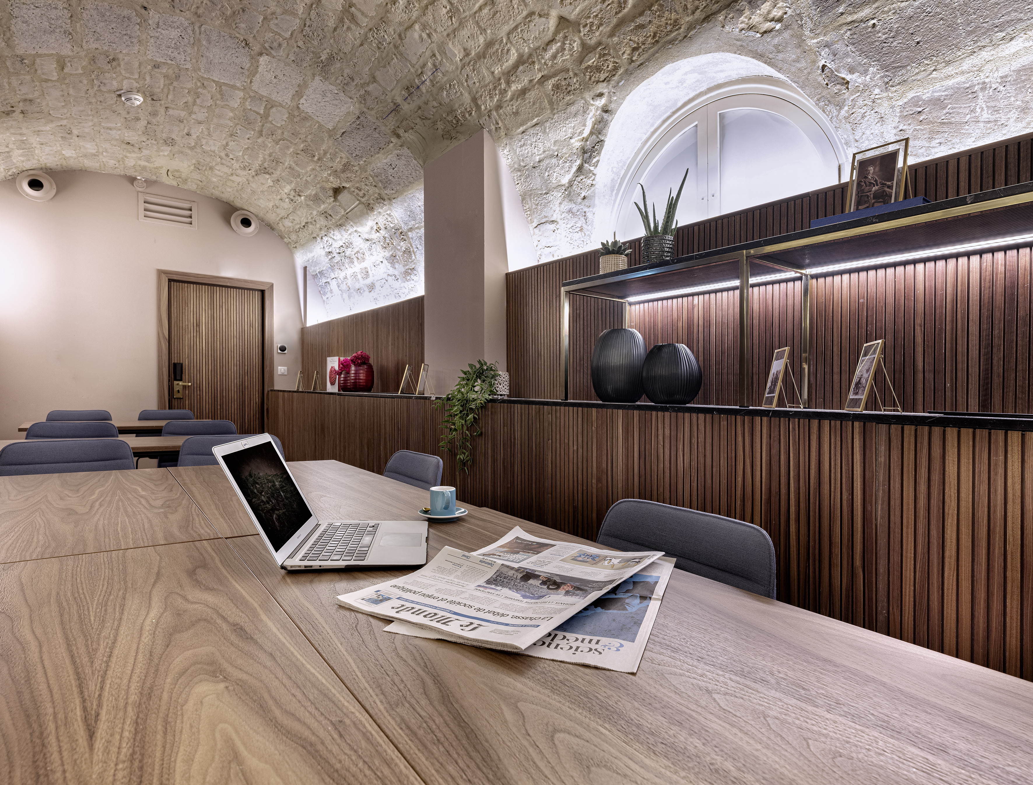 Modern meeting room with vaulted stone ceiling, wood accents, and laptop.