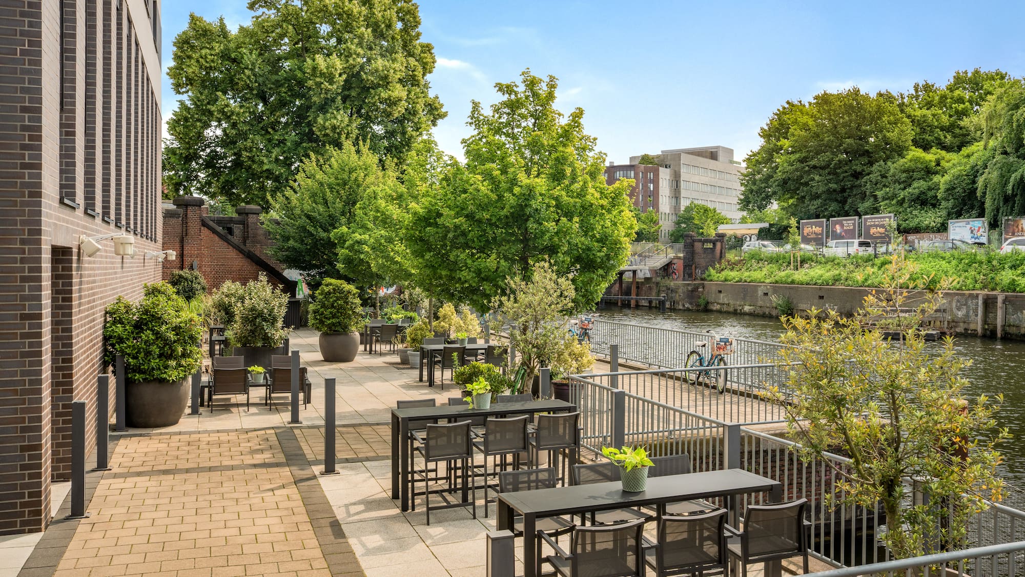 a patio with tables and chairs and trees by a river