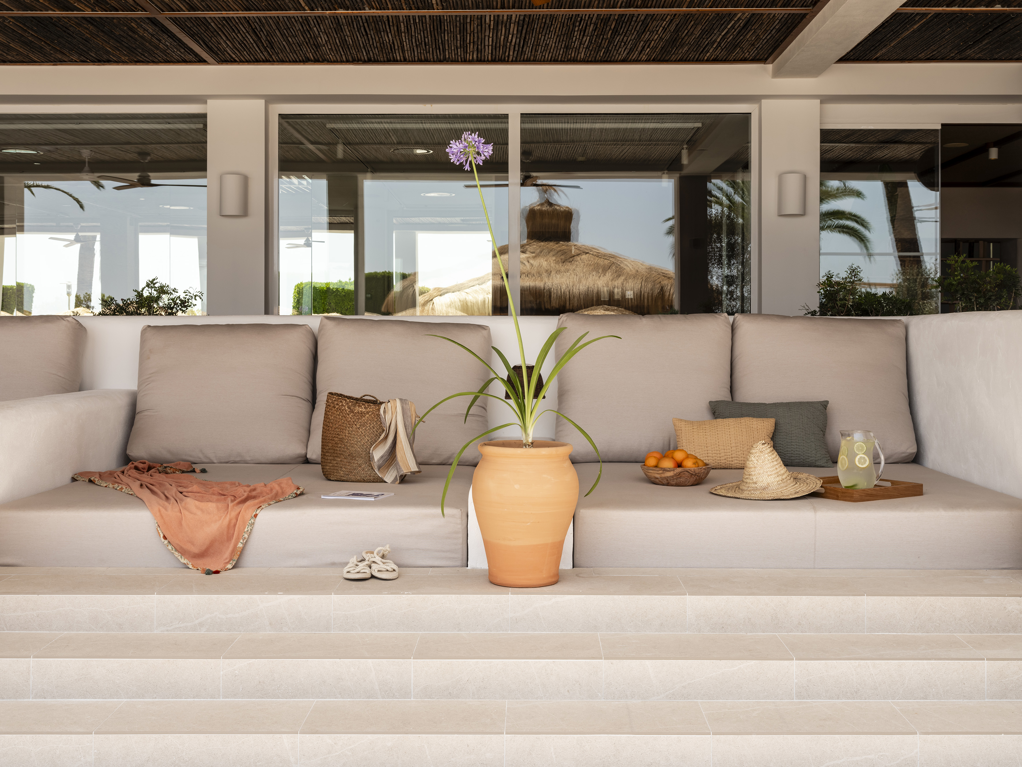 Outdoor patio lounge with Agapanthus in terracotta pot, resort reflections.