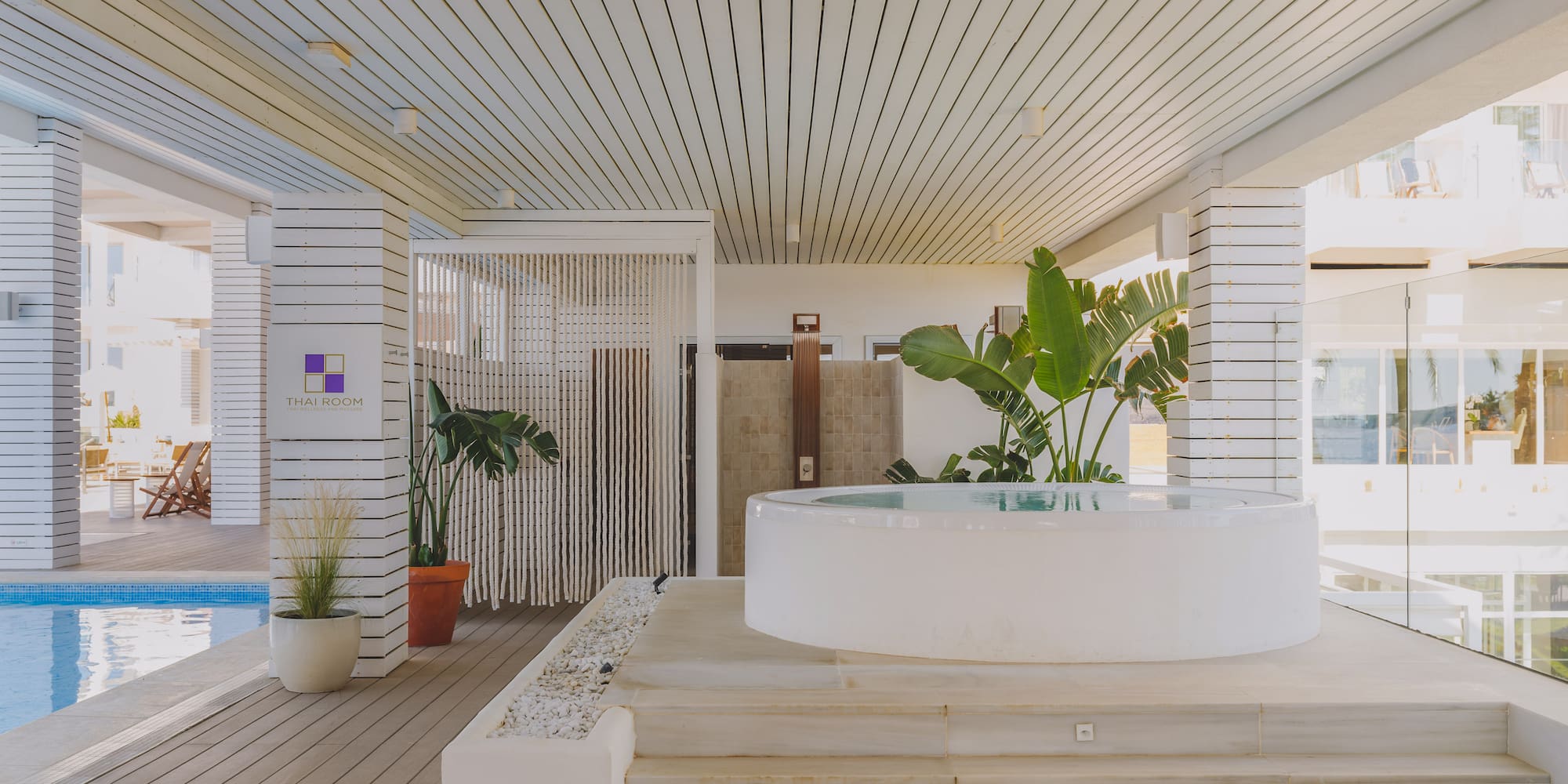 Resort spa with white round hot tub, pool, wooden deck, and Thai Room sign.