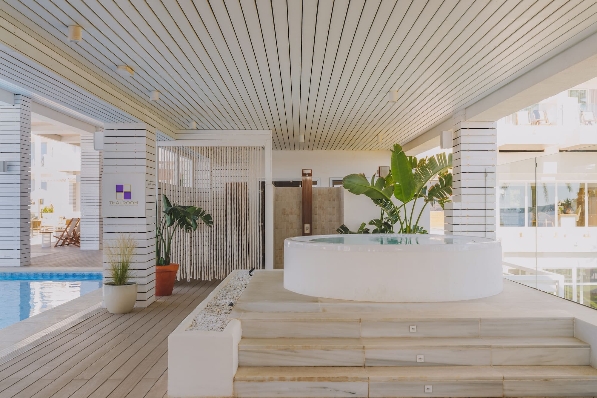 Outdoor resort spa with white hot tub, poolside wooden deck, and Thai Room sign.