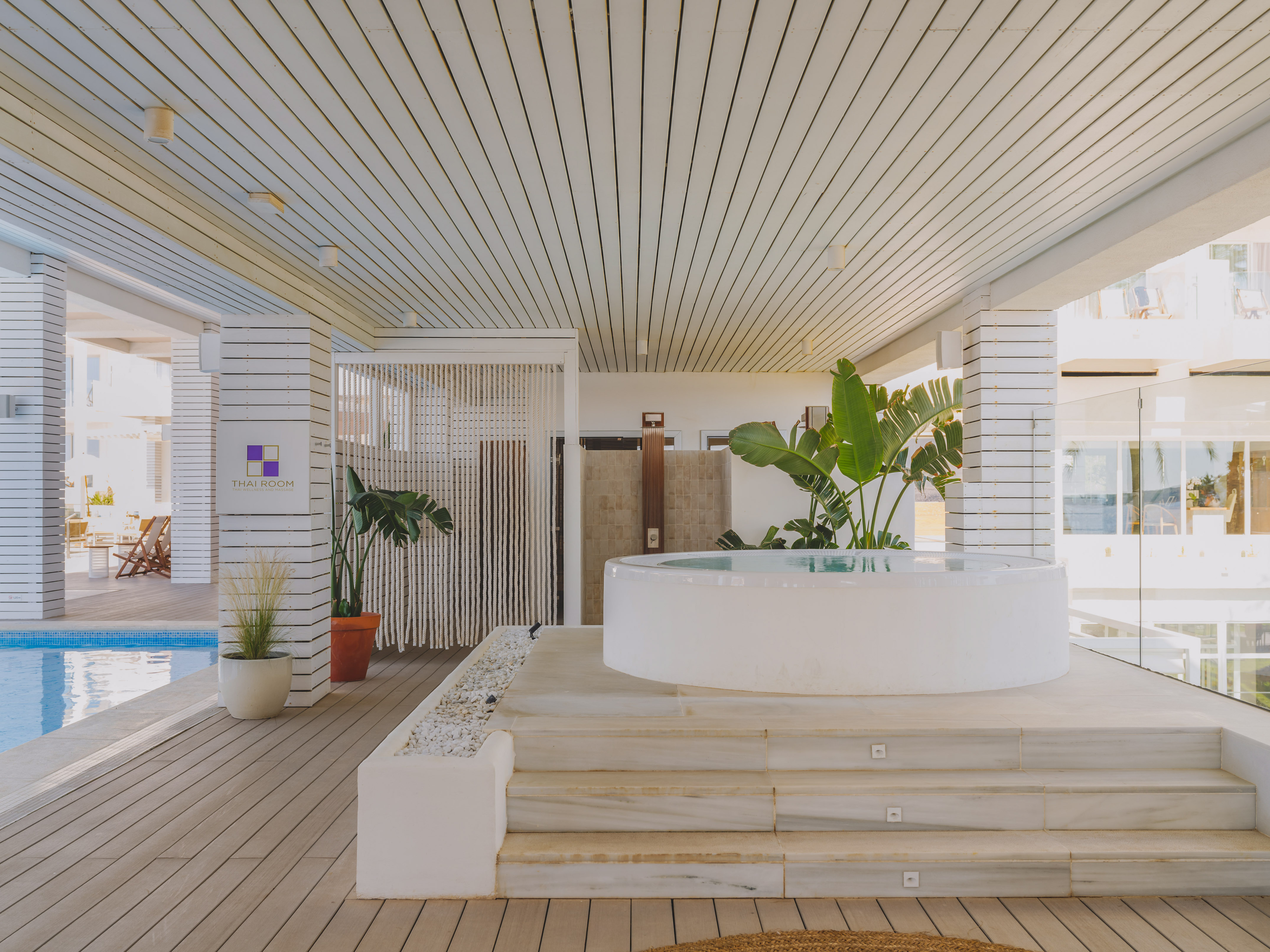Outdoor resort spa with white hot tub, poolside wooden deck, and Thai Room sign.