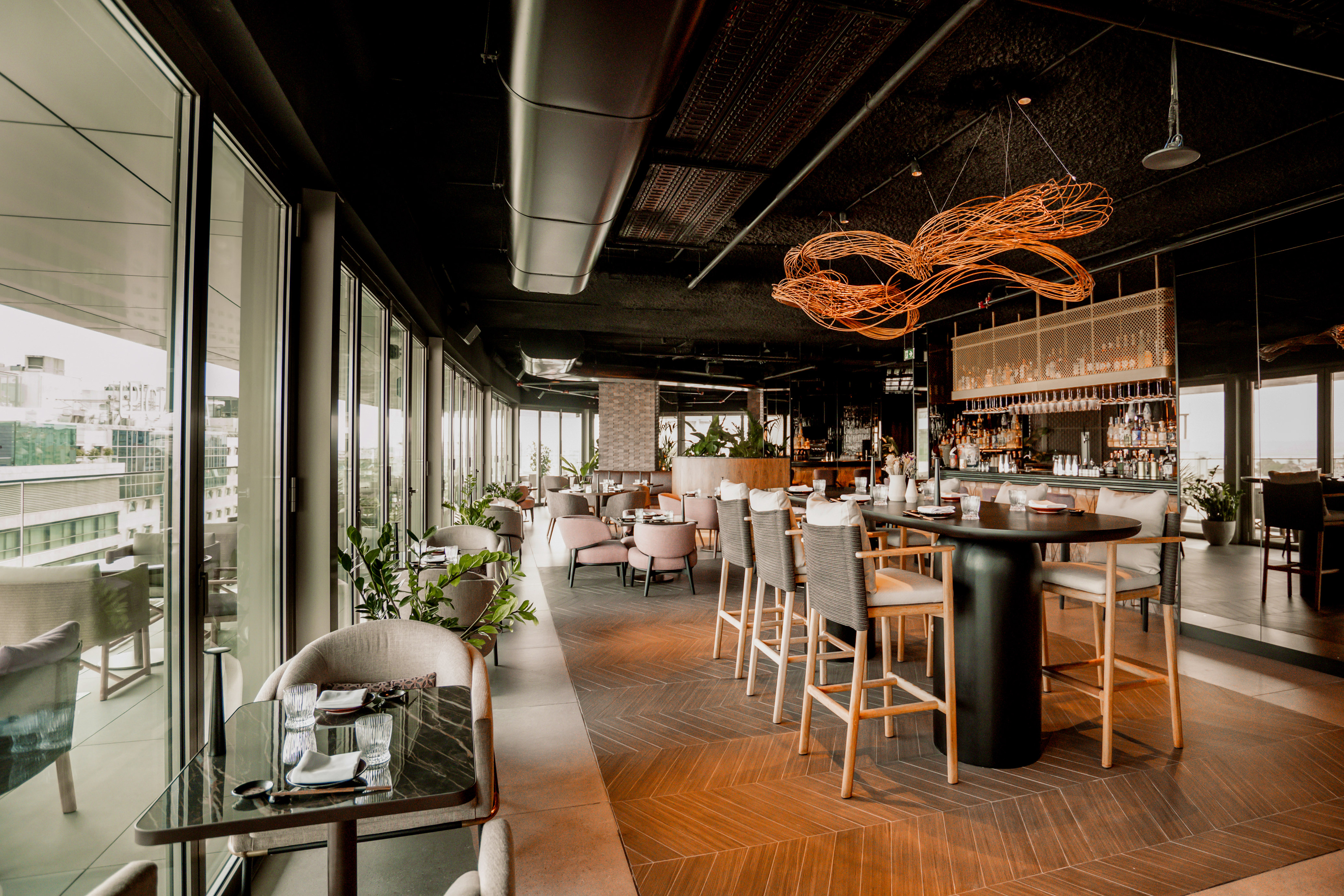 Modern upscale restaurant interior with city view, bar, and stylish seating.