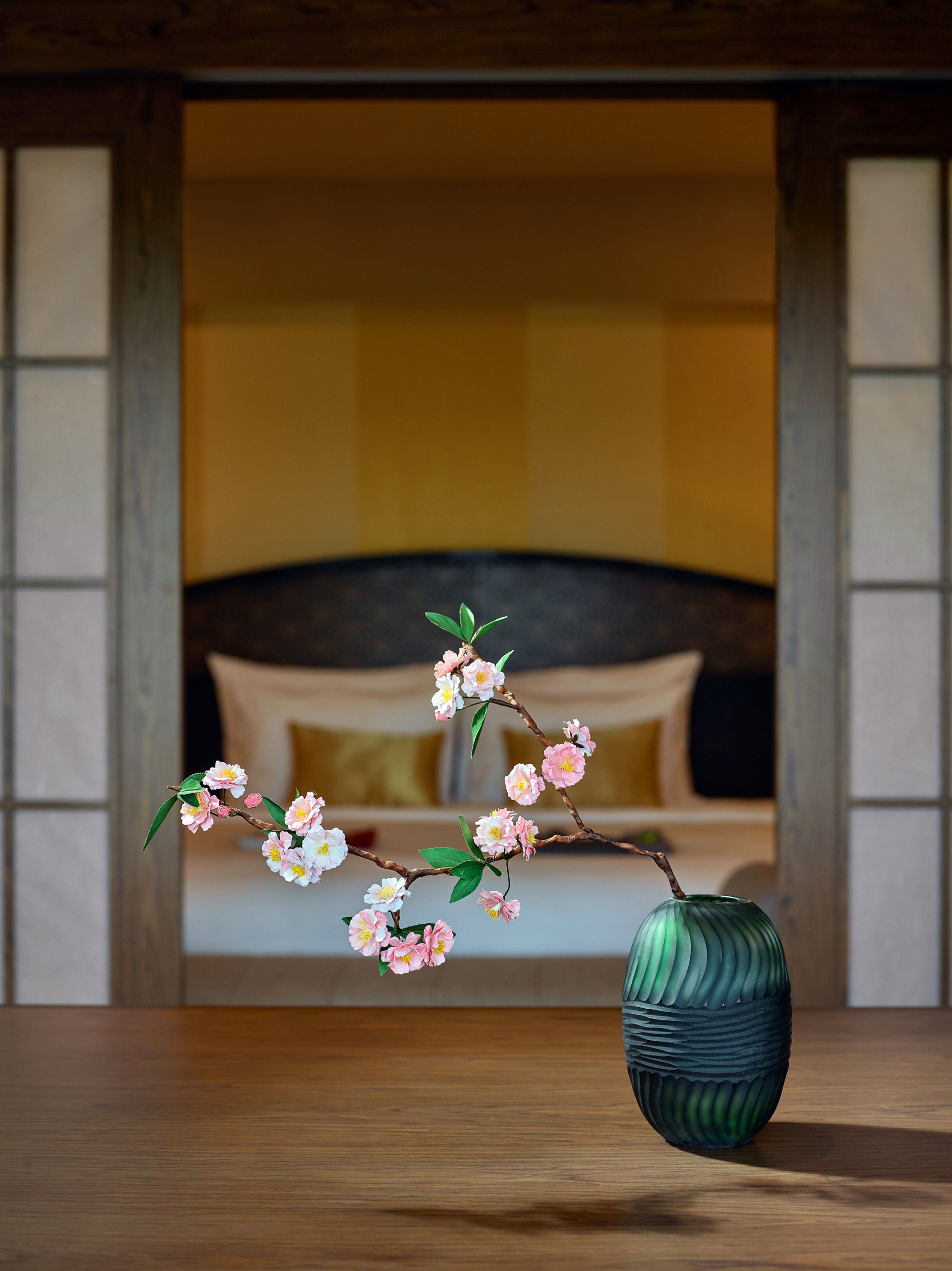 Cherry blossom branch in green vase on wood, Japanese bedroom decor.