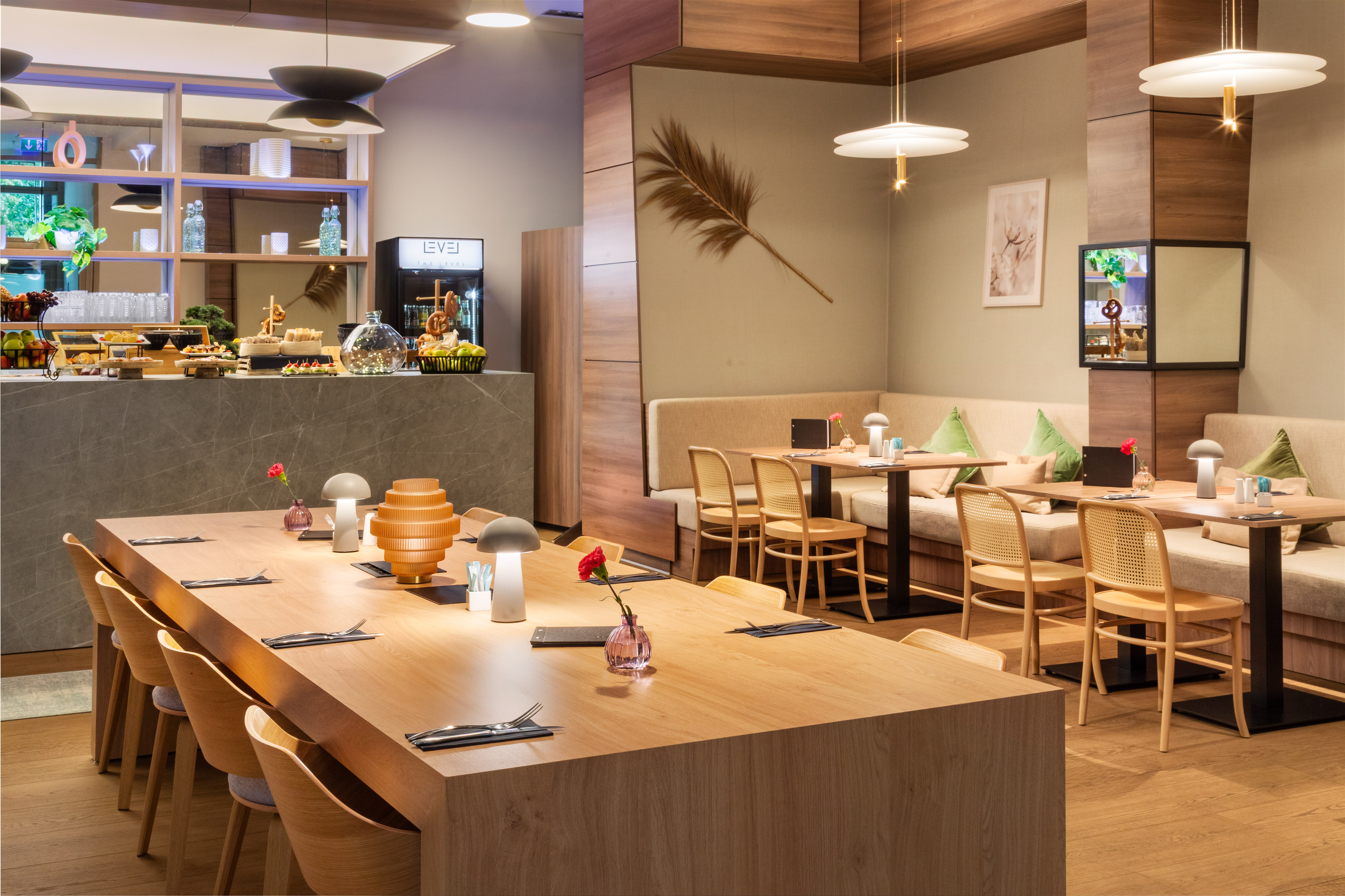 Modern hotel dining room with buffet, communal table, and booth seating.