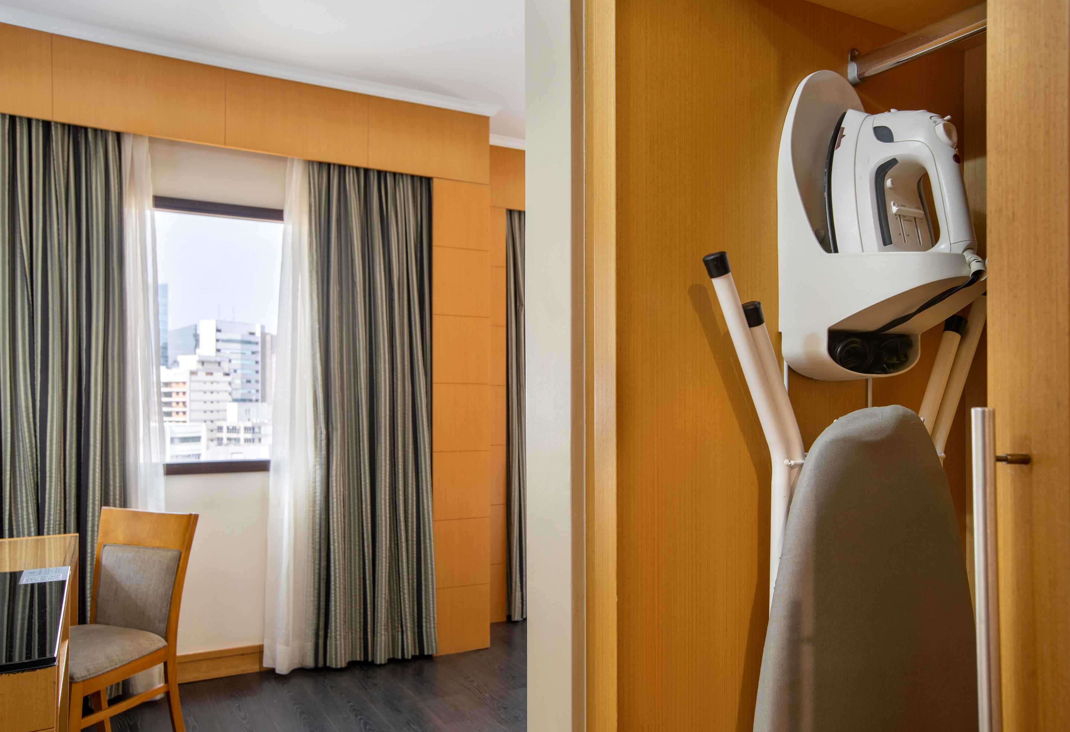Hotel room amenities: iron, ironing board in closet, city view from window.