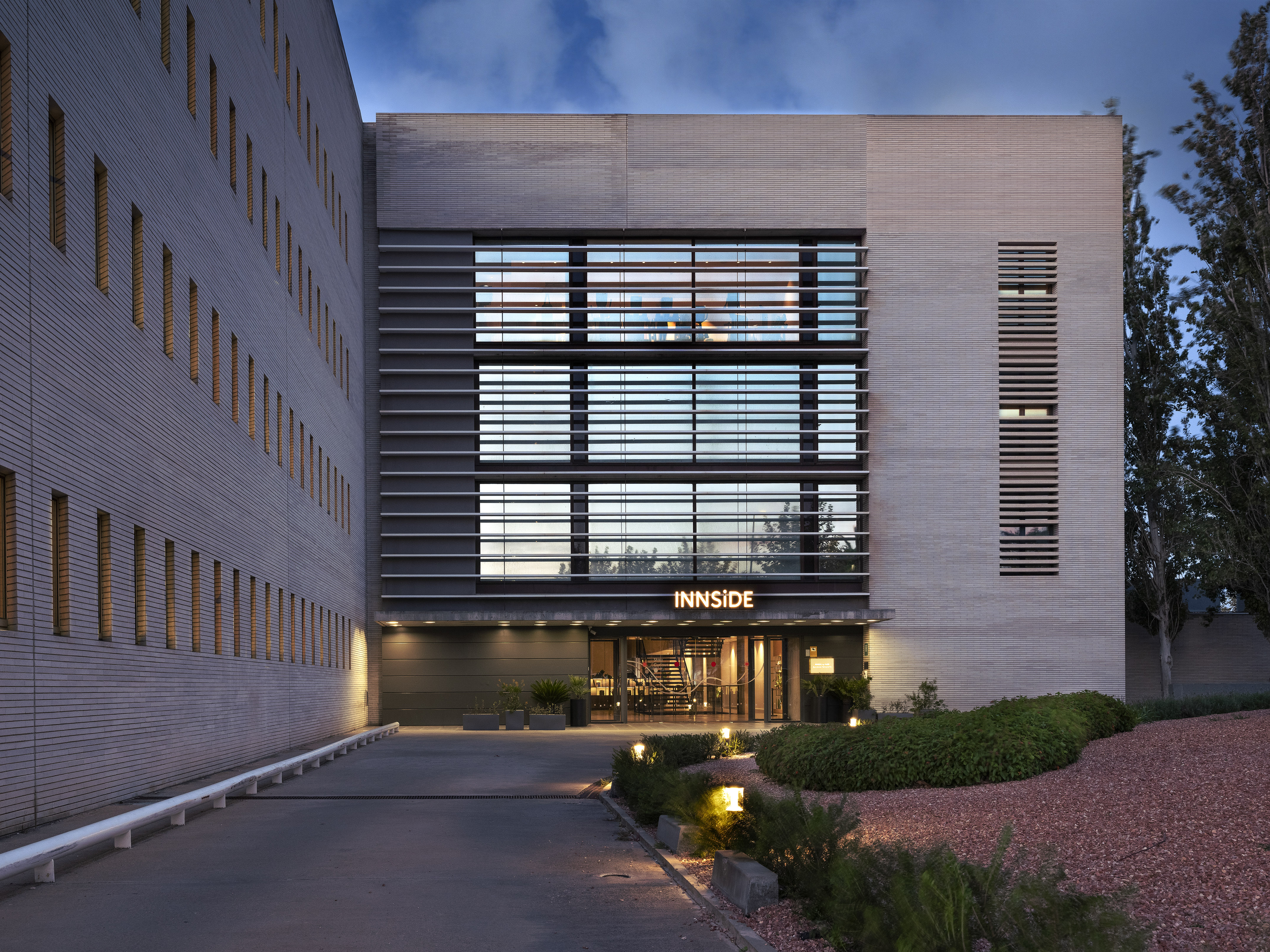 Modern INNSiDE hotel exterior at dusk, illuminated entrance and windows.