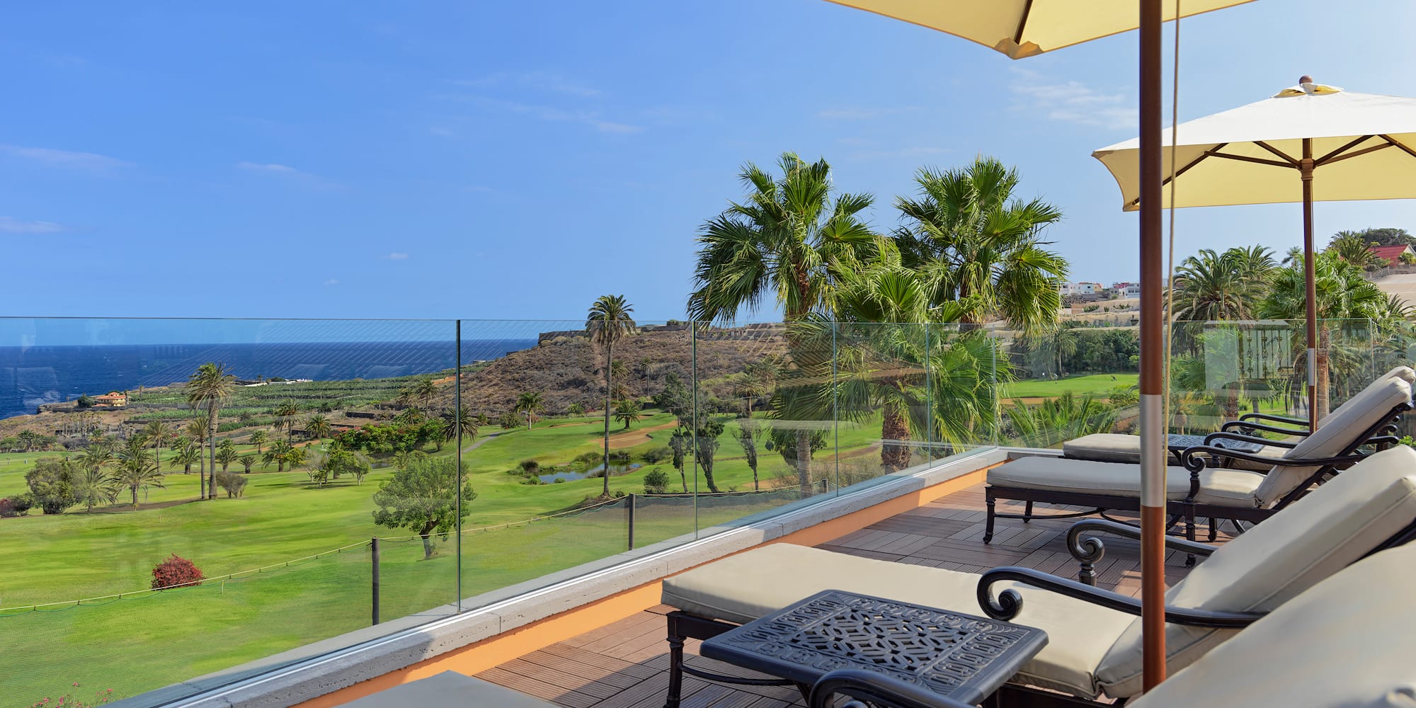 a deck with chairs and umbrellas overlooking a golf course
