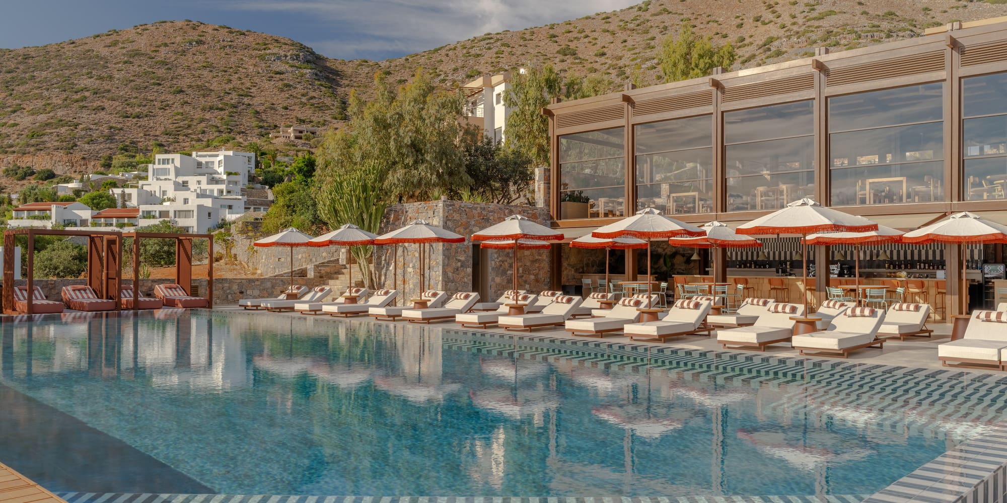 a pool with umbrellas and chairs in front of a building