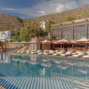 a pool with umbrellas and chairs in front of a building