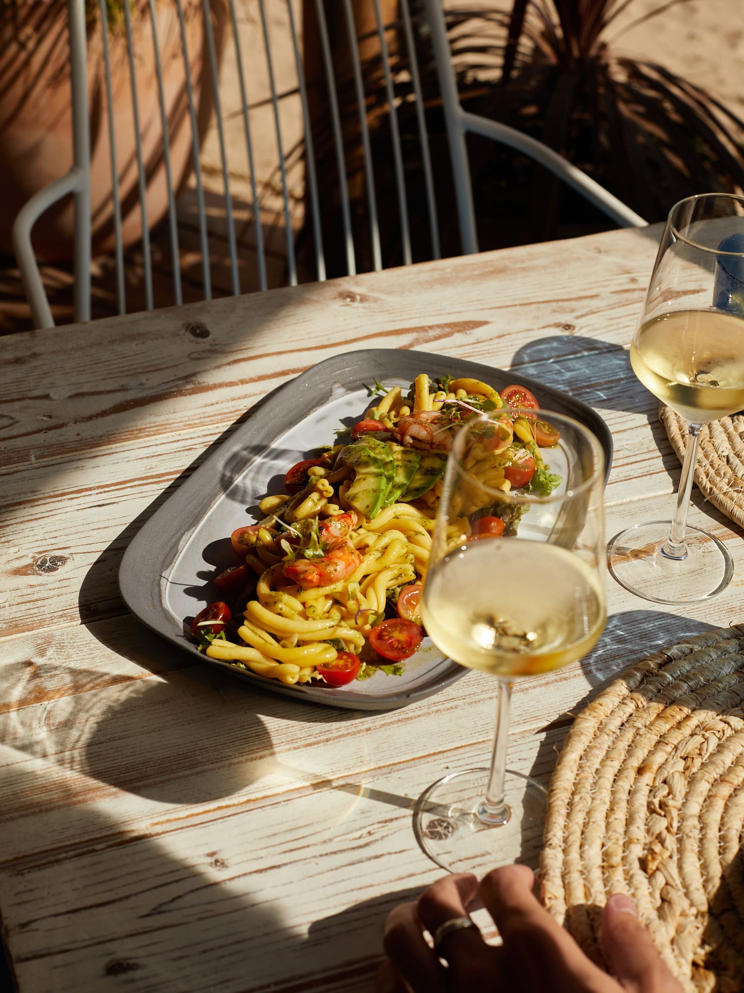 Pesto pasta salad with shrimp, avocado, tomatoes, white wine, outdoor dining.