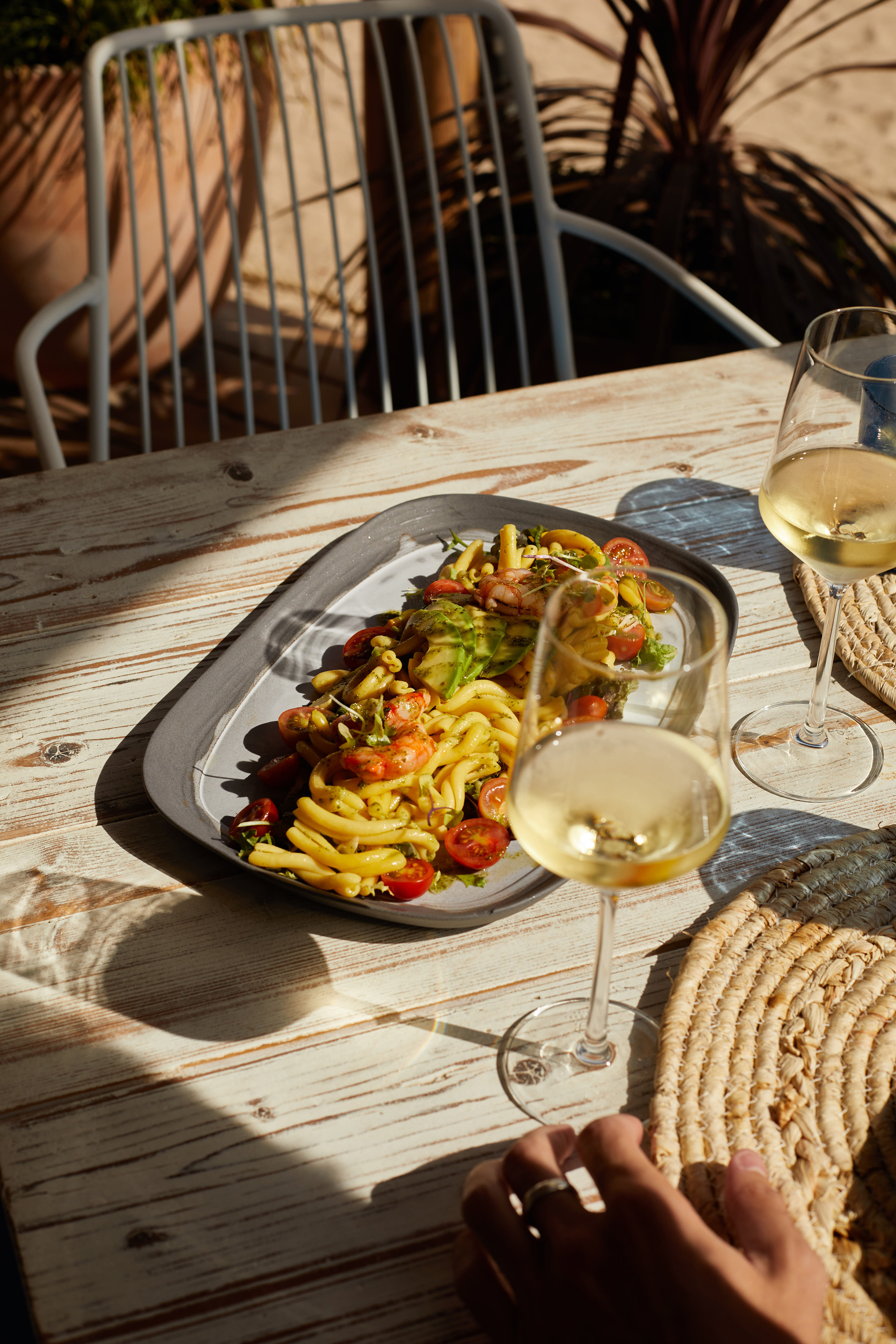 Pesto pasta salad with shrimp, avocado, tomatoes, white wine, outdoor dining.