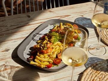a plate of pasta and wine glasses on a table