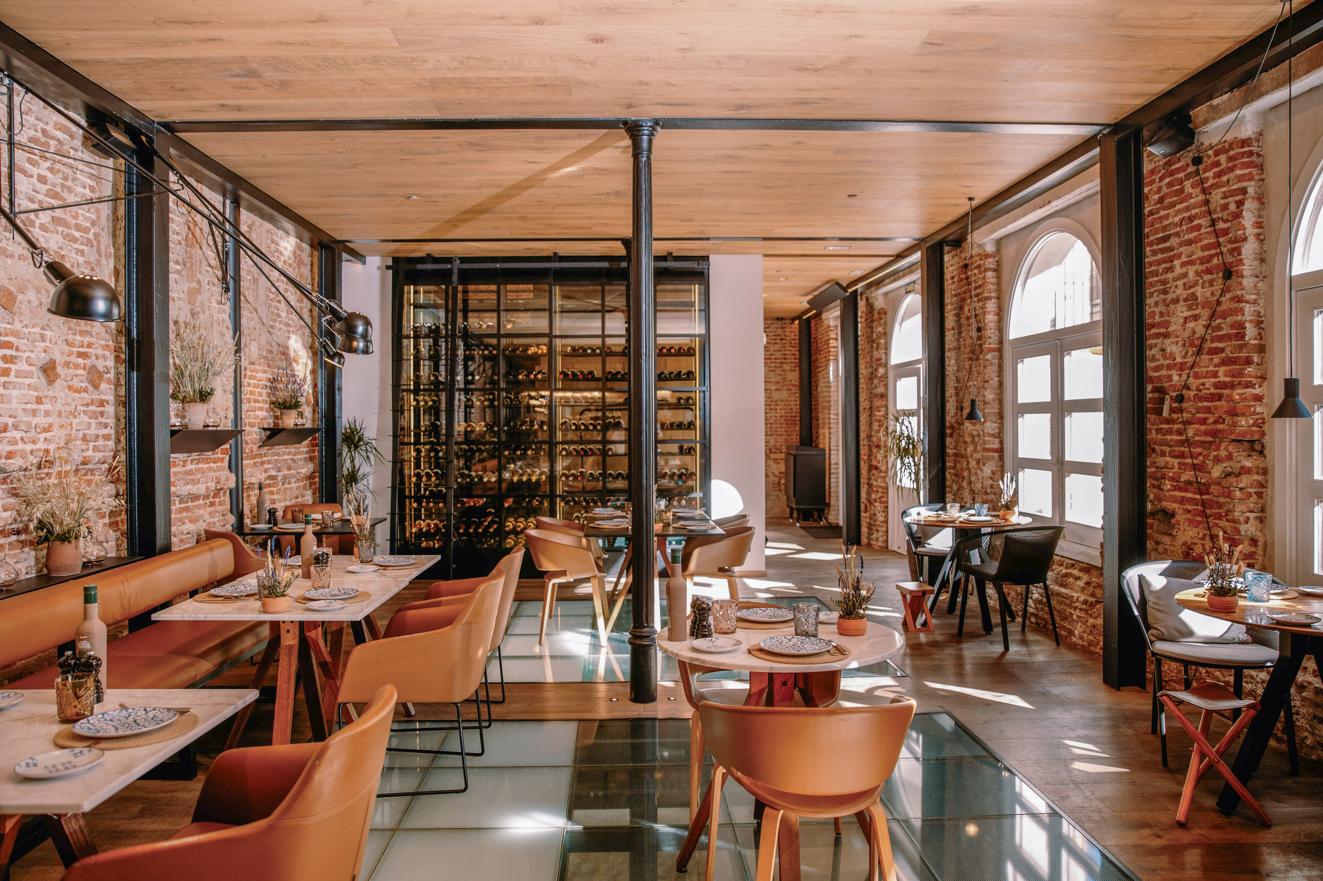 Industrial chic restaurant interior: brick walls, wine cellar, modern dining tables.