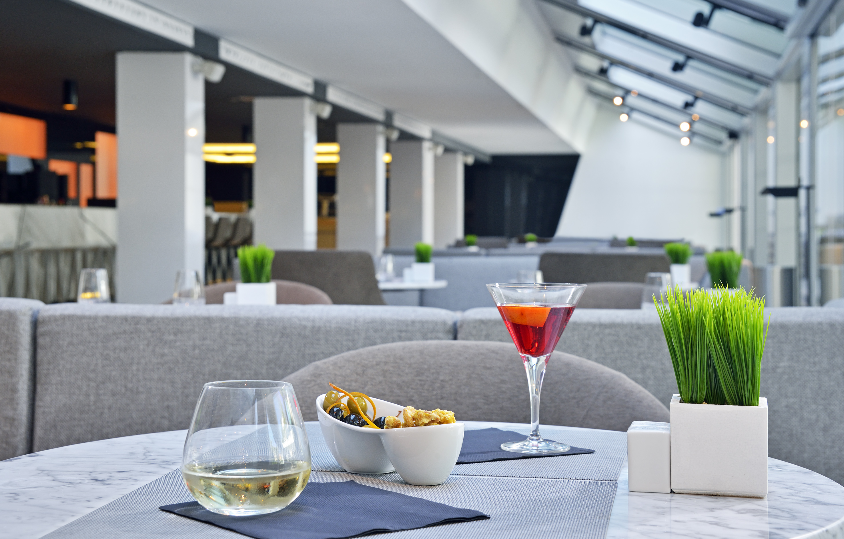 Modern lounge table with wine, cocktail, snacks, and stylish bar interior.