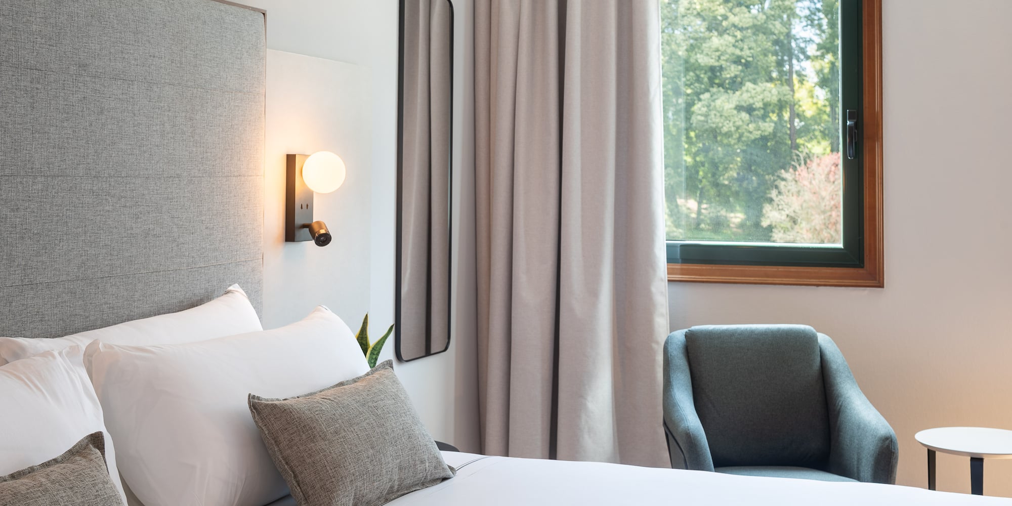 a bed with pillows and a chair in a room with a window