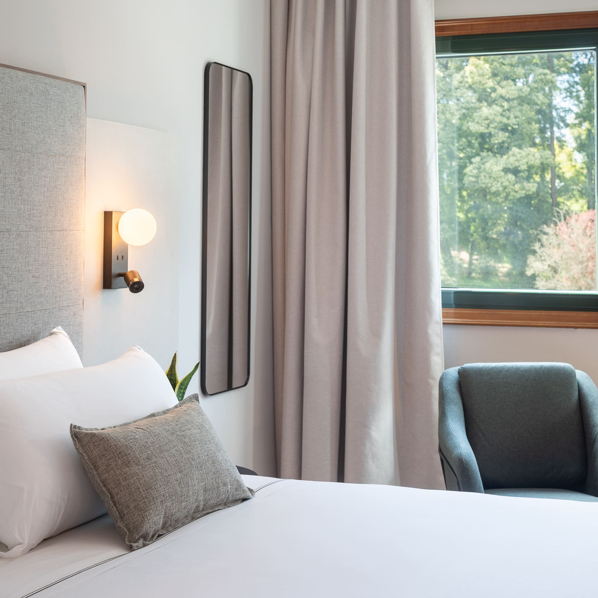 a bed with pillows and a chair in a room with a window