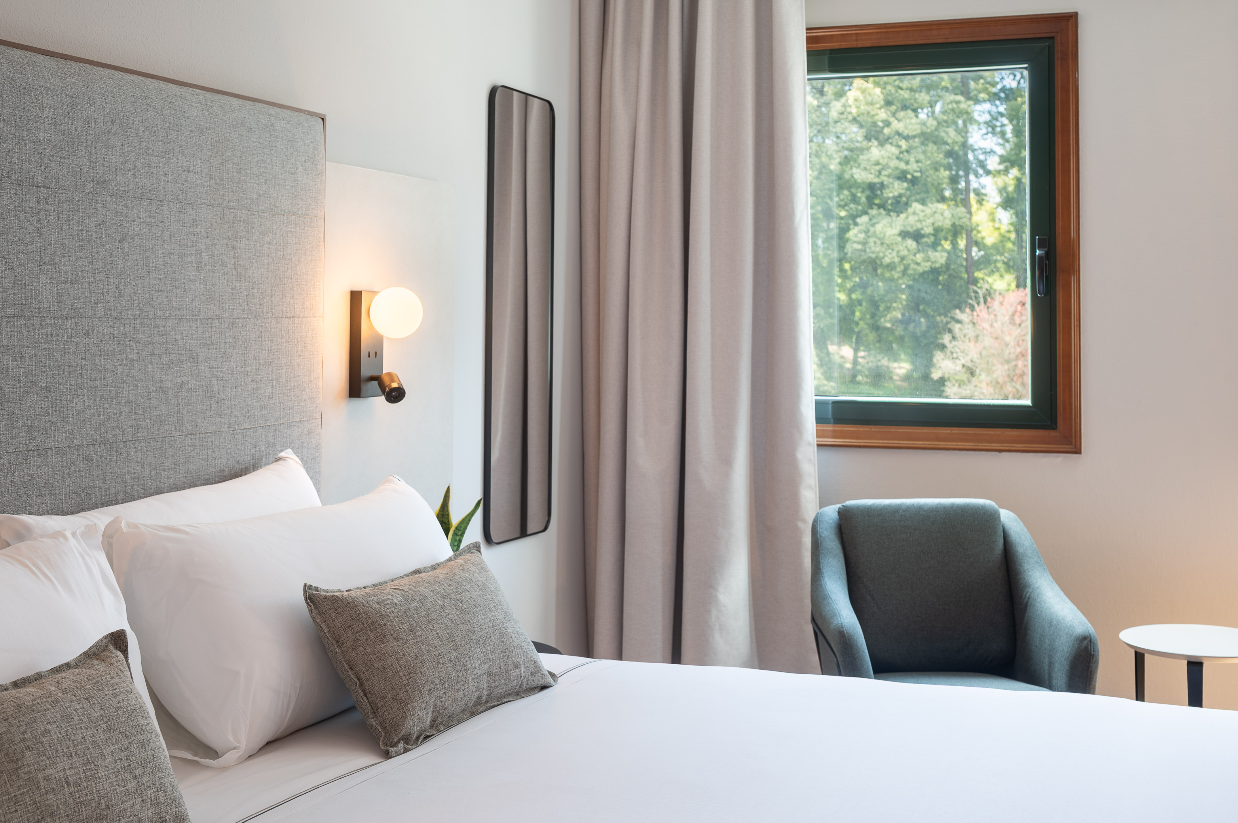 a bed with pillows and a chair in a room with a window