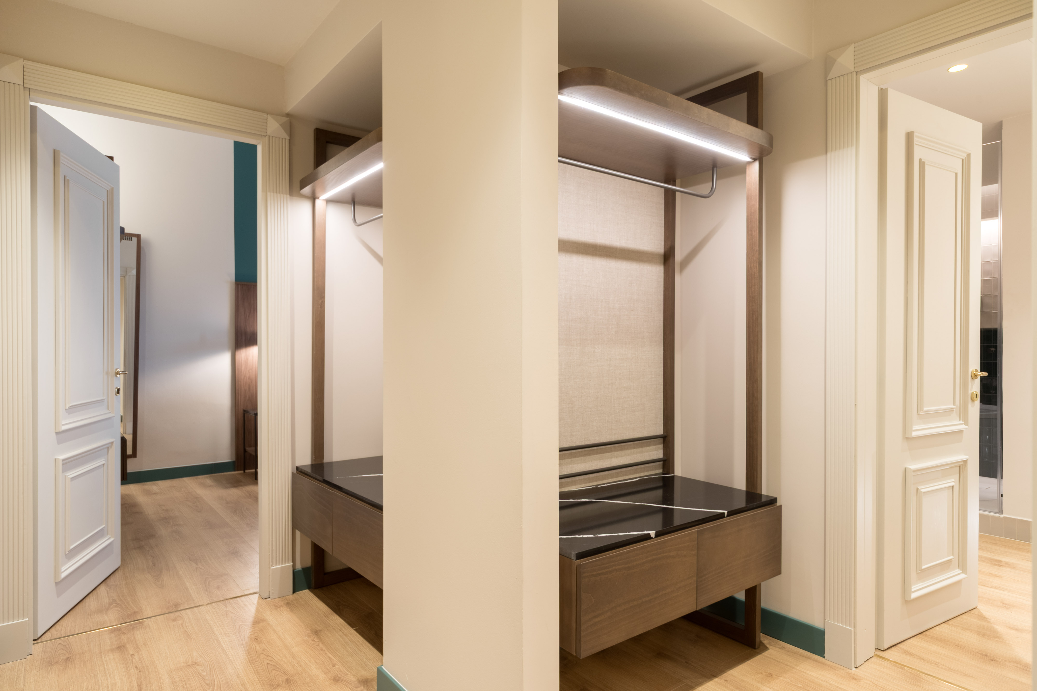 Modern hotel entrance with built-in illuminated wardrobe and marble counter.