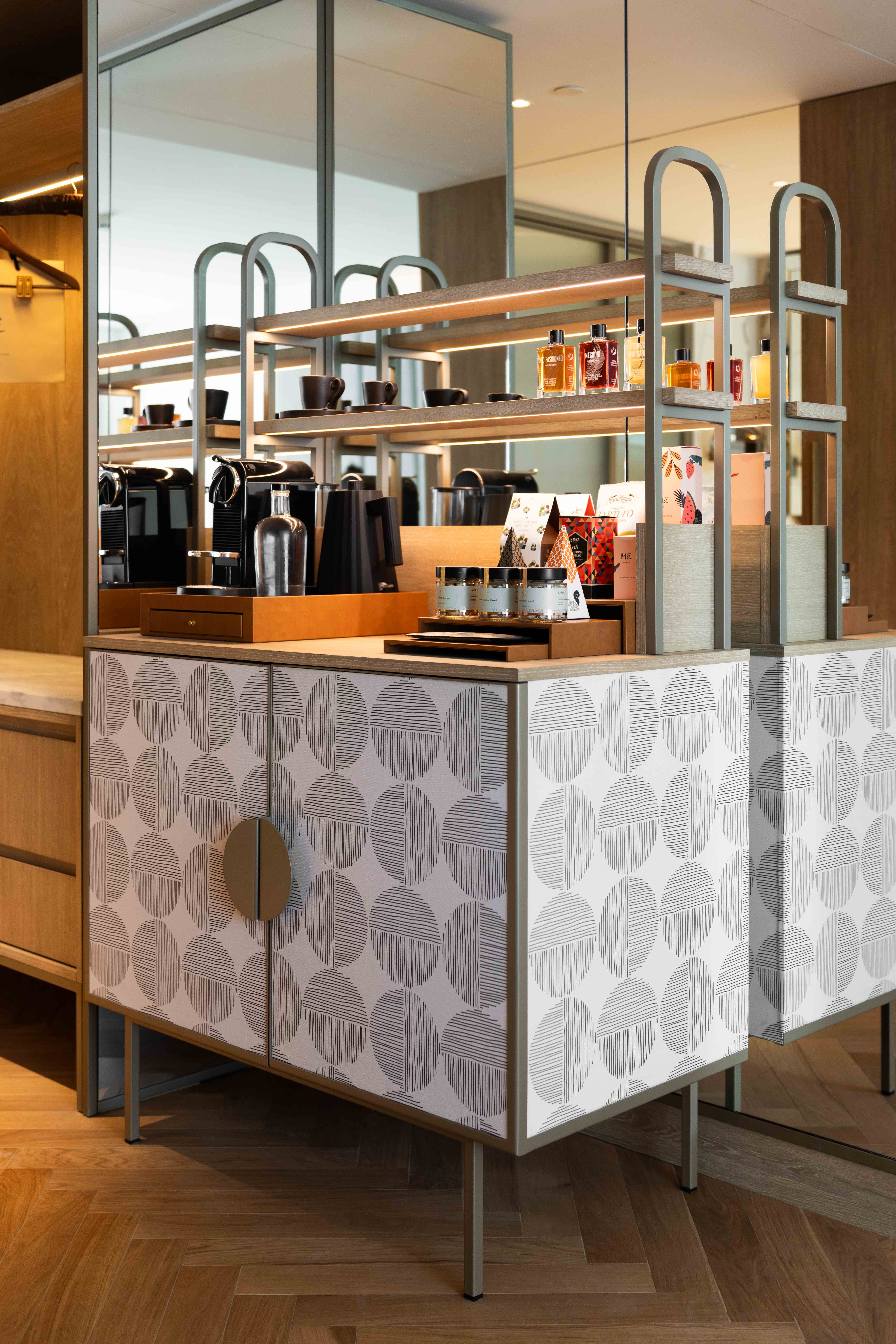 Elegant hotel mini-bar with Nespresso, liquor bottles, and modern patterned cabinet.