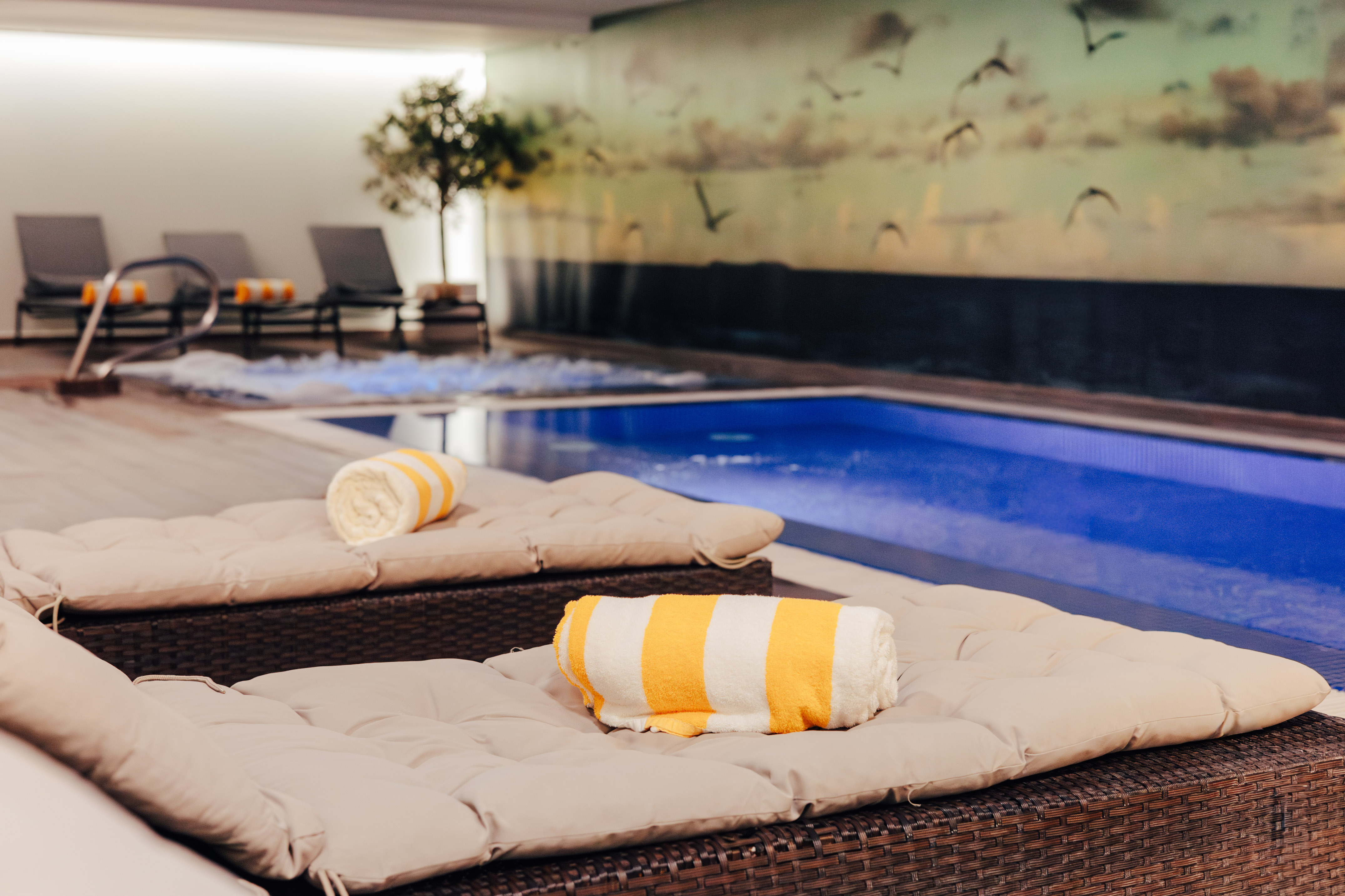 Indoor spa pool, jacuzzi, and lounge chairs with yellow striped towels.