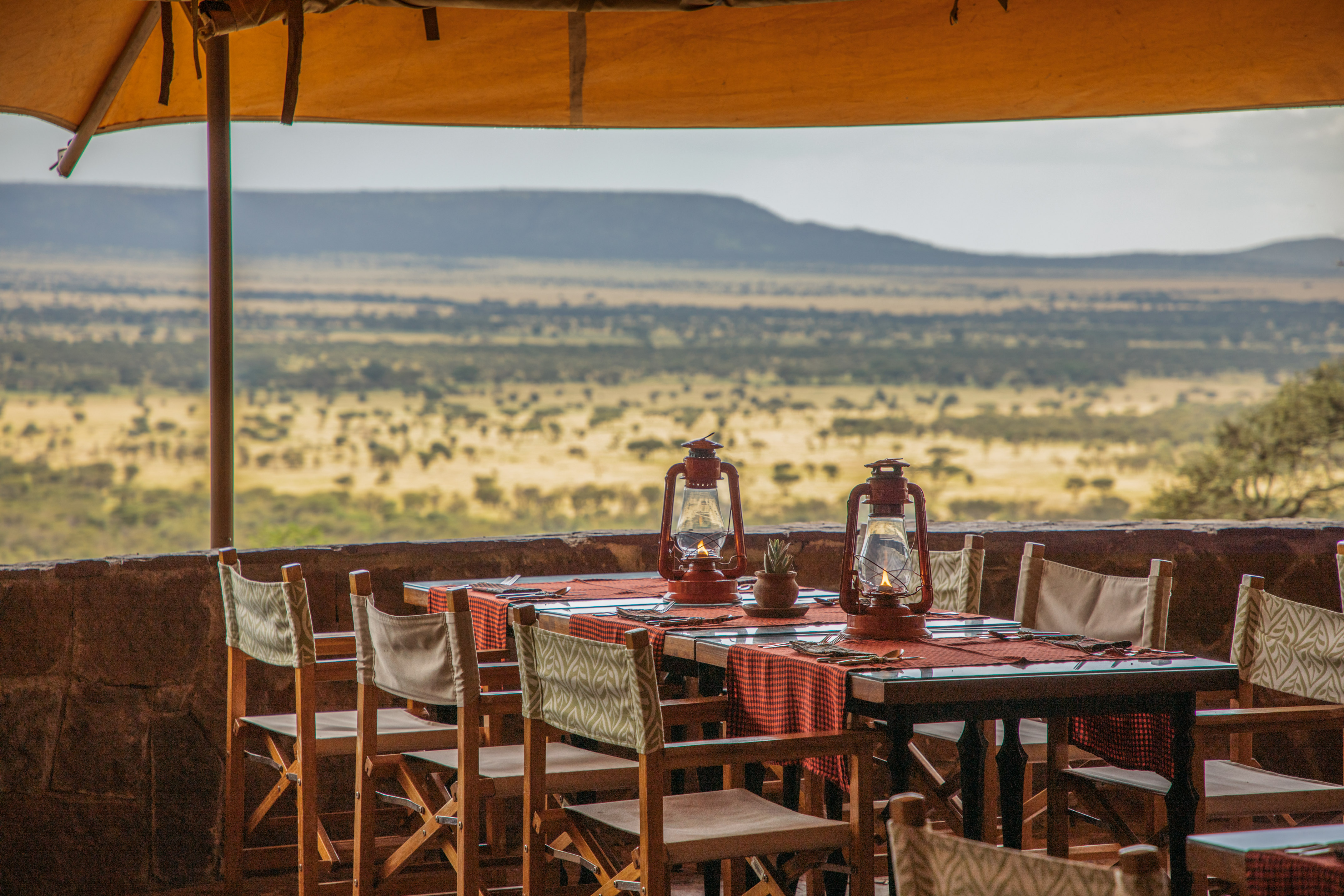 Scenic safari lodge dining table with lanterns and a panoramic savanna view.