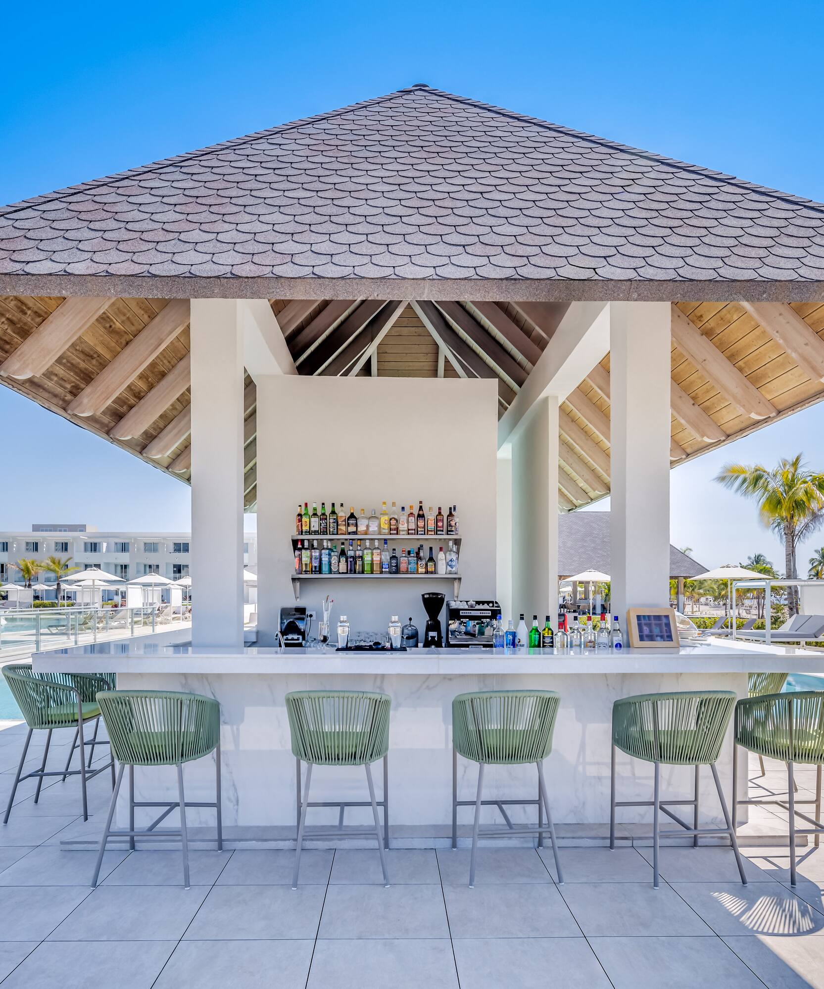a bar with a bar and chairs by a pool