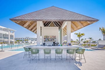 a bar with a bar and chairs by a pool
