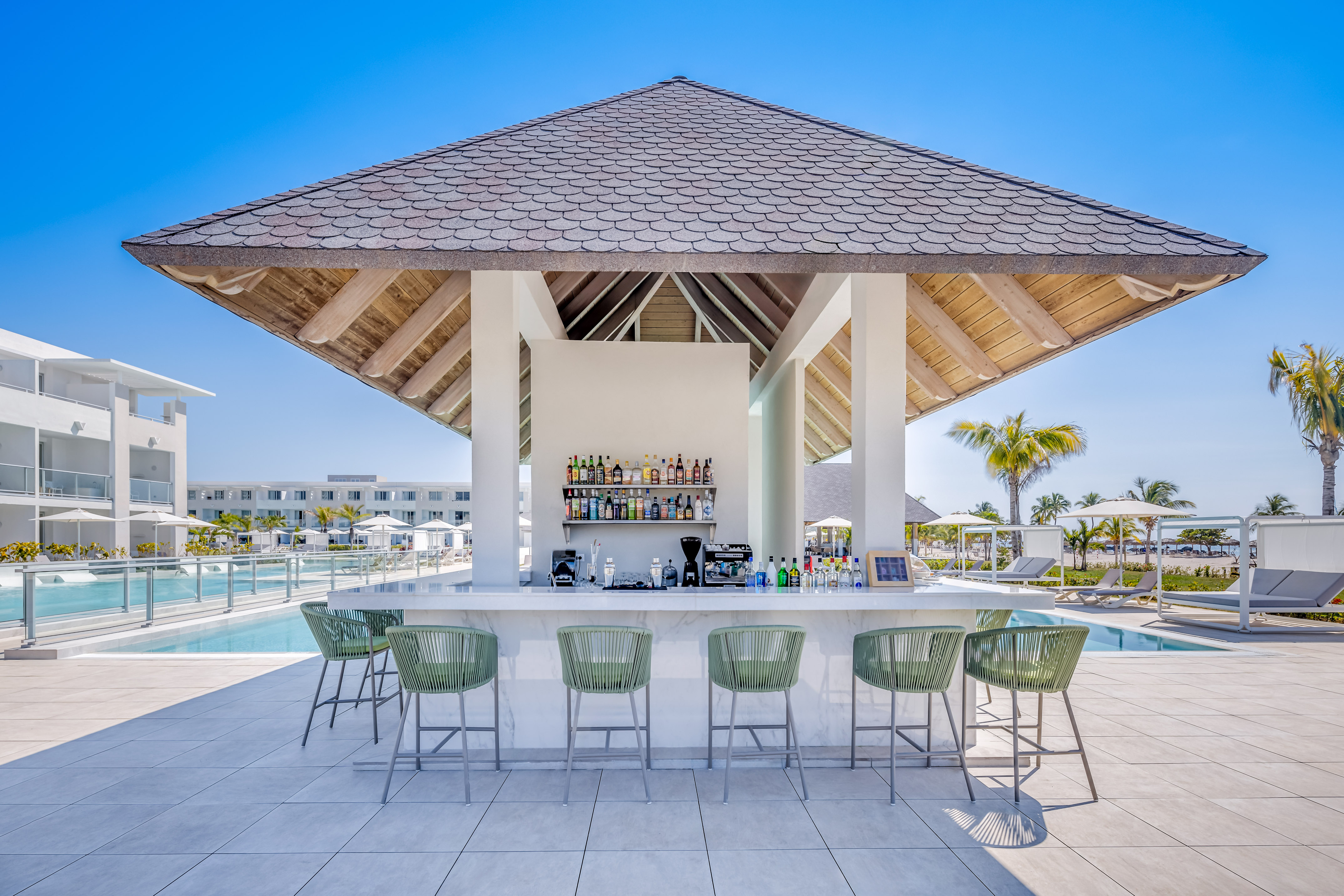 a bar with a bar and chairs by a pool