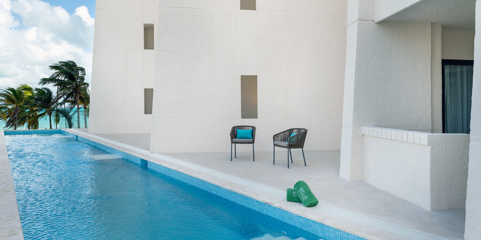 a pool with chairs and a green mat