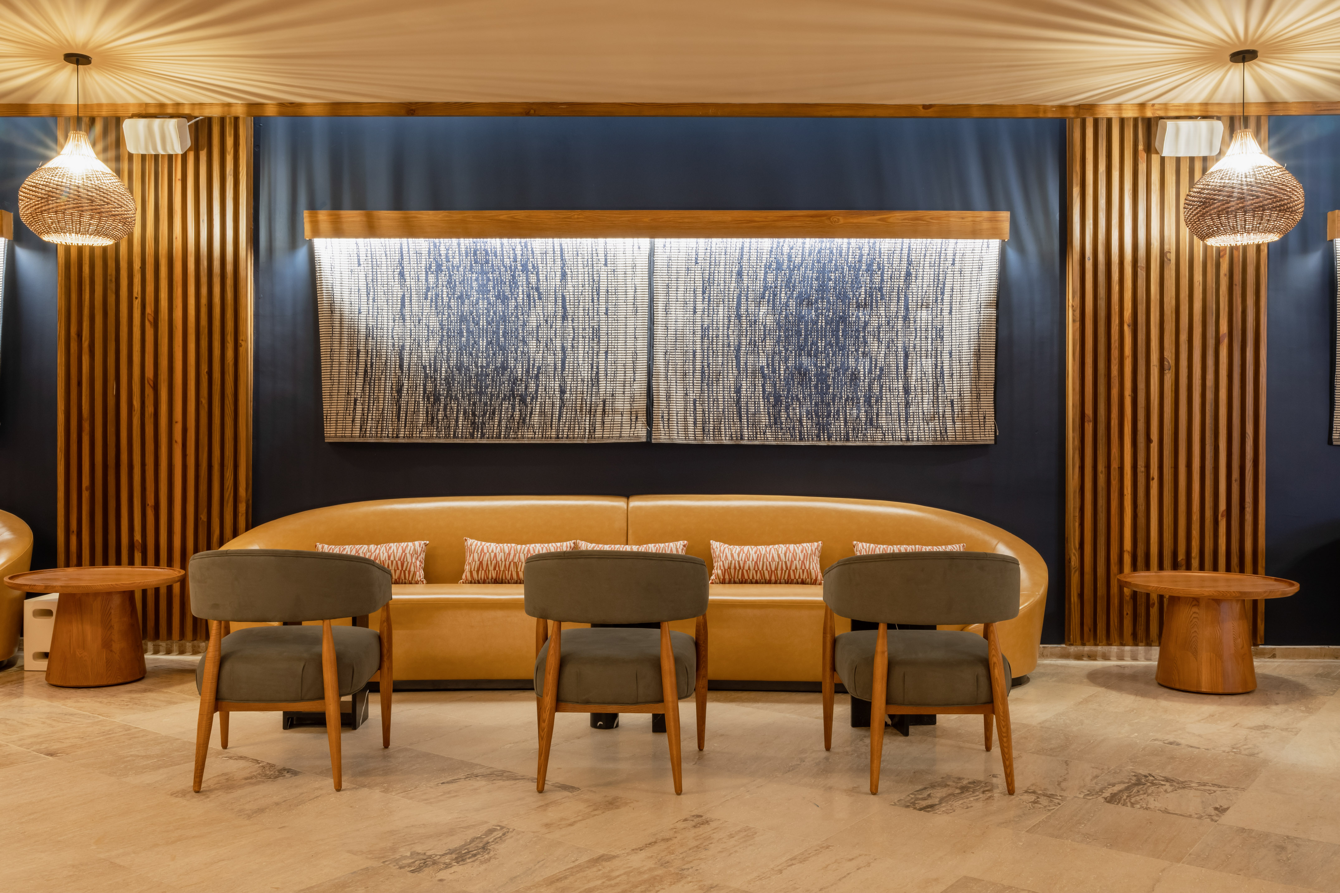 Modern lounge area with tan sofa, green chairs, wooden accents & abstract art.