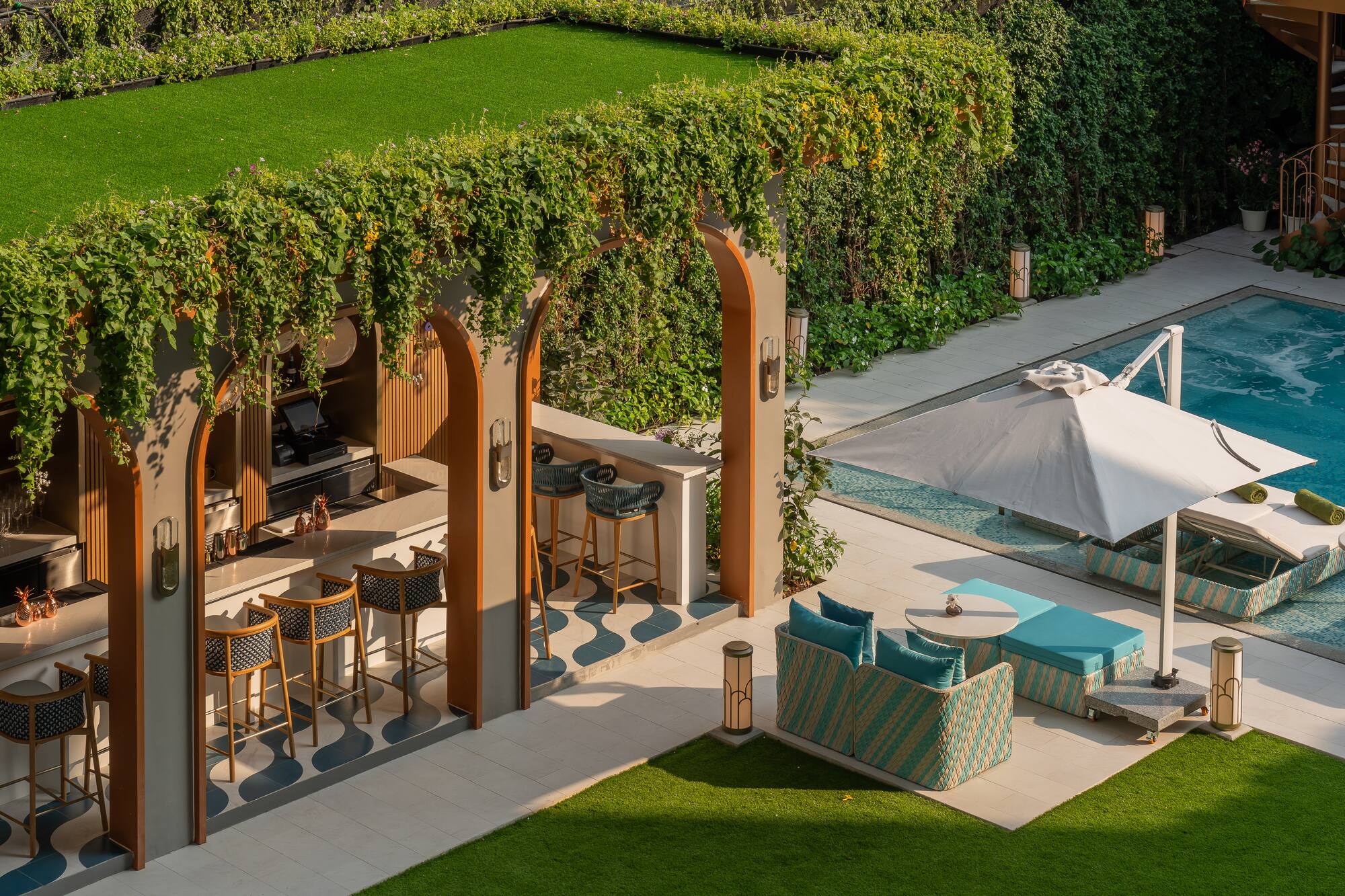 Lush outdoor bar and poolside lounge with swimming pool and green turf.