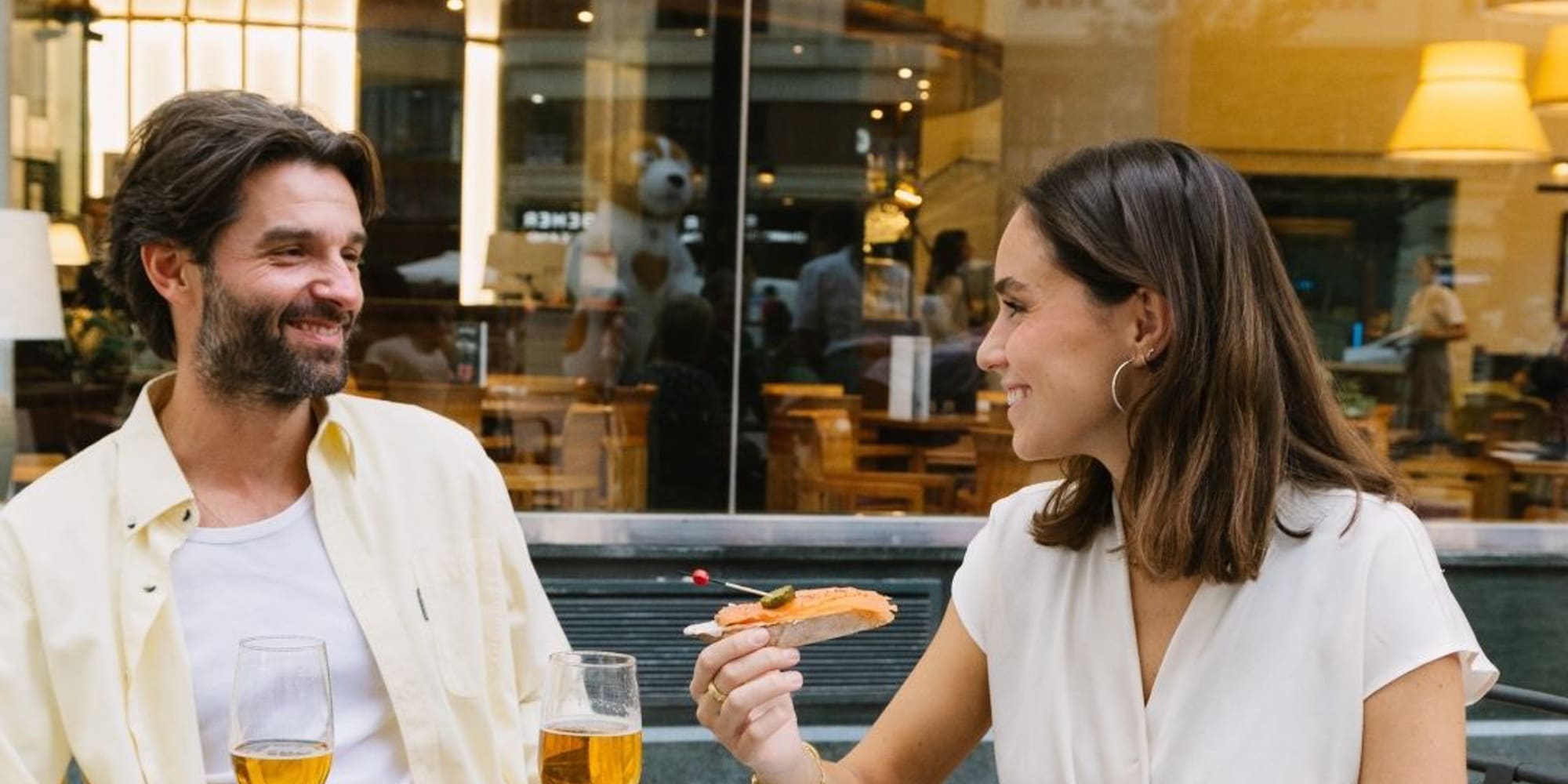 a man and woman sitting at a table with food and drinks