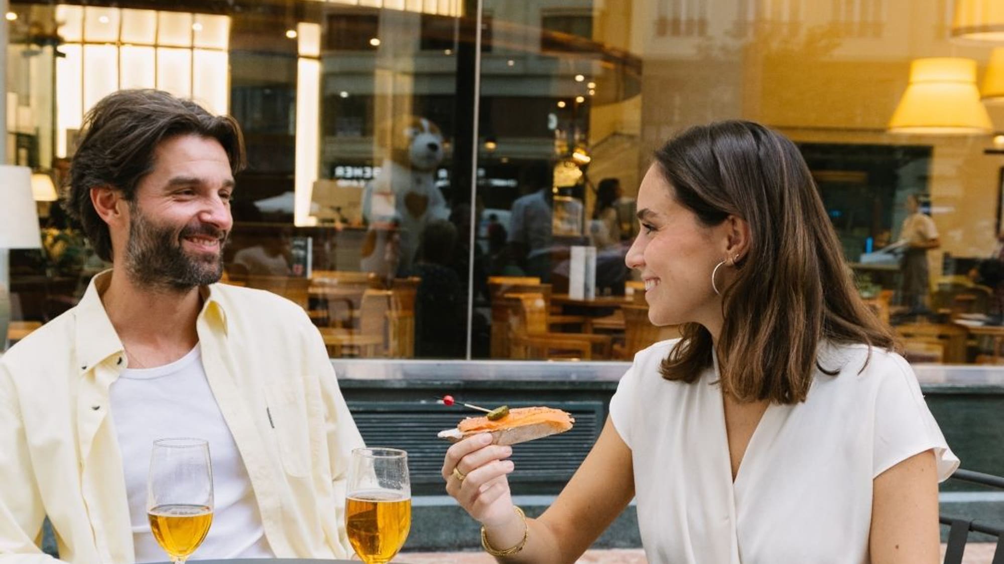 a man and woman sitting at a table with food and drinks