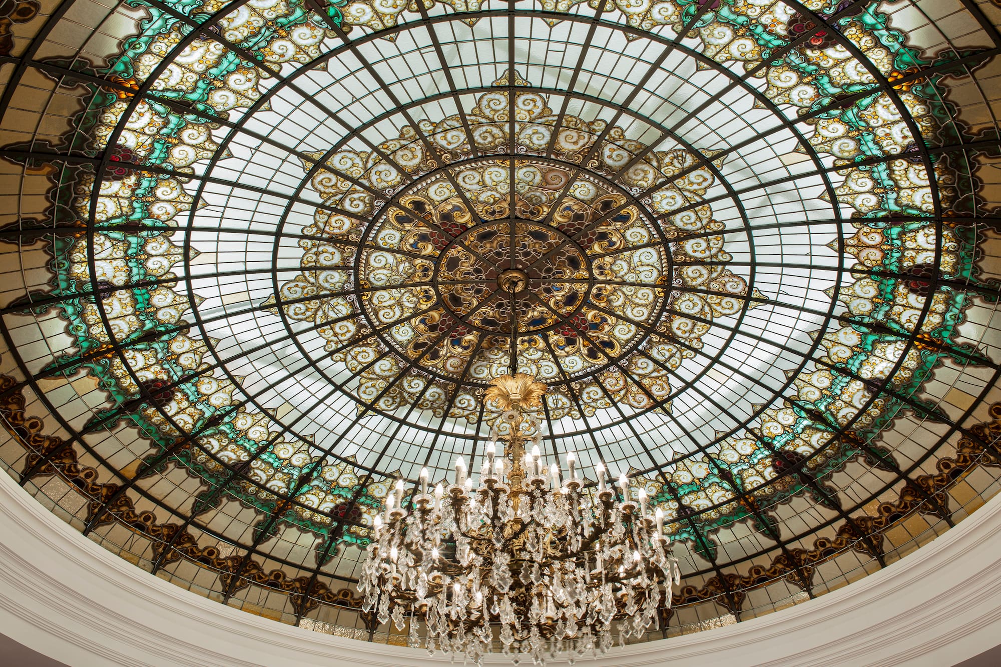 Art Nouveau stained glass dome ceiling with ornate crystal chandelier.