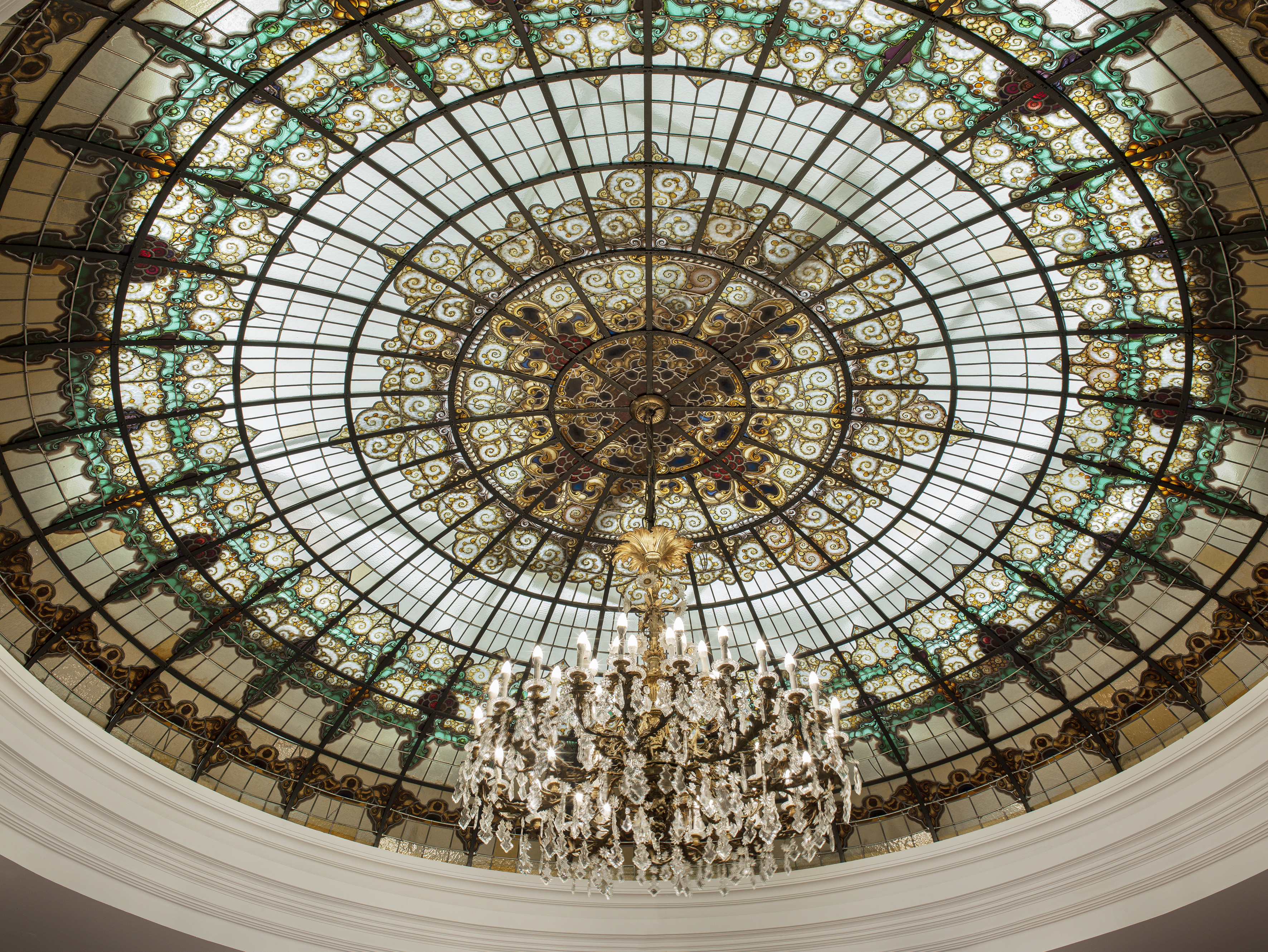 Art Nouveau stained glass dome ceiling with ornate crystal chandelier.